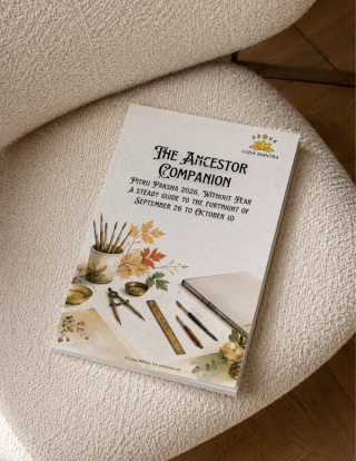 Luna Mantra The Ancestor Companion Pitru Paksha 2026 guide mockup lying on a cream bouclé armchair above a wooden herringbone floor, its cover showing watercolour autumn leaves, brushes and warm neutral home styling.