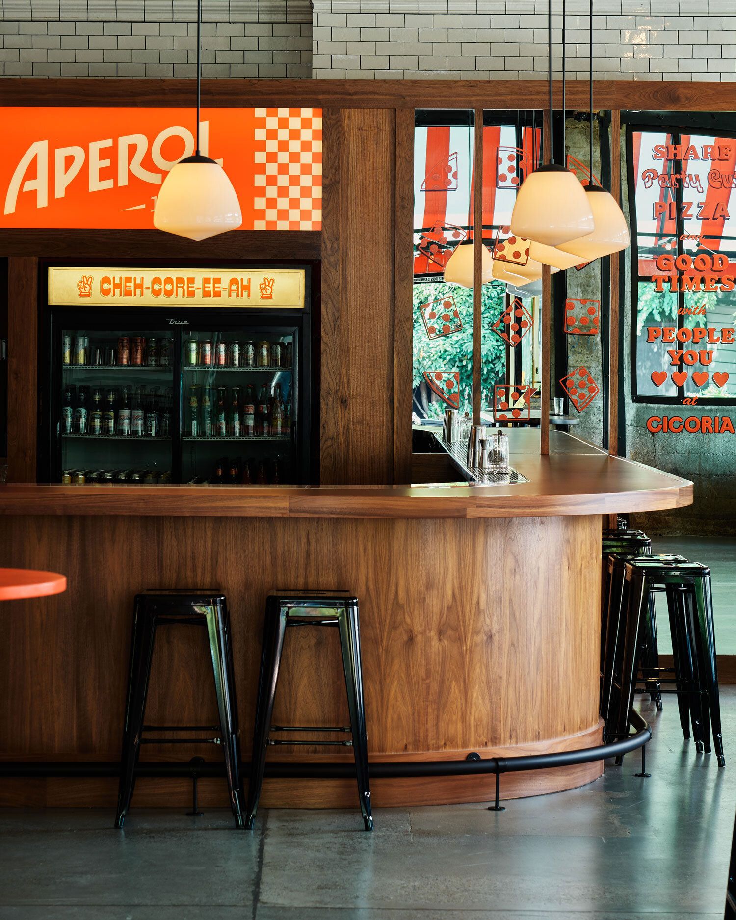 The bar sits empty at Cicoria ready to host customers. A sign reads "Aperol" above a fridge stacked with beverages.