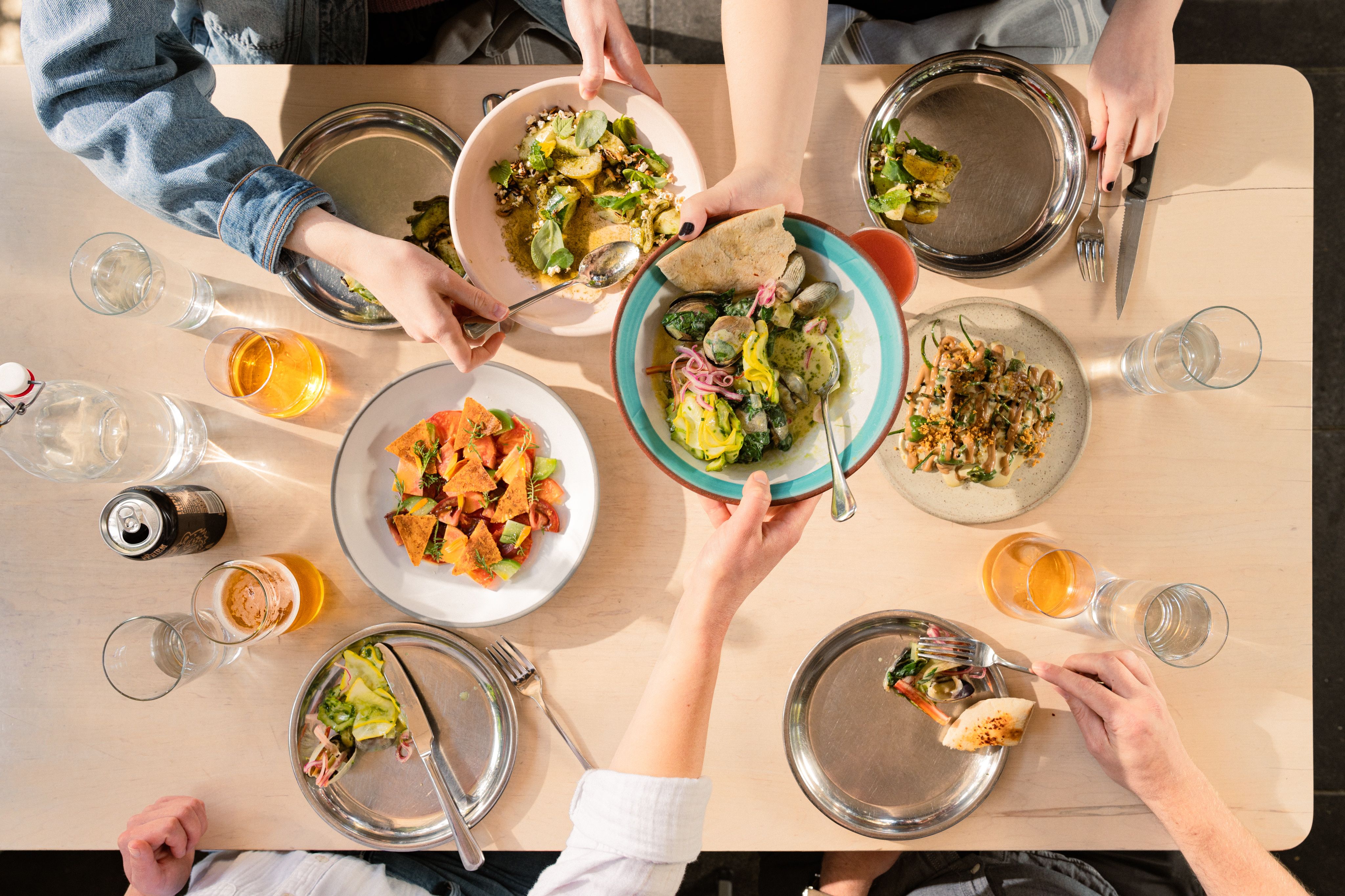 A group of friends sharing a table of beautiful vegetable dishes.