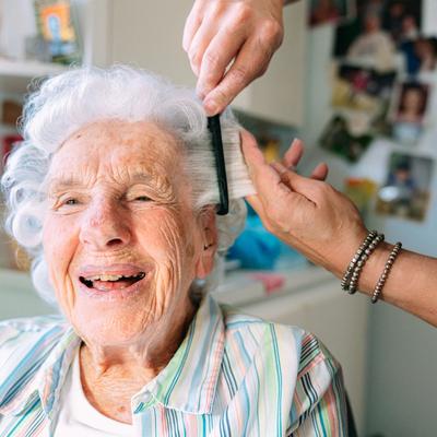 Eldre dame får håret stelt av en frisør