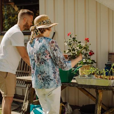 En ung mann og en eldre dame står ute og potter om planter og blomster