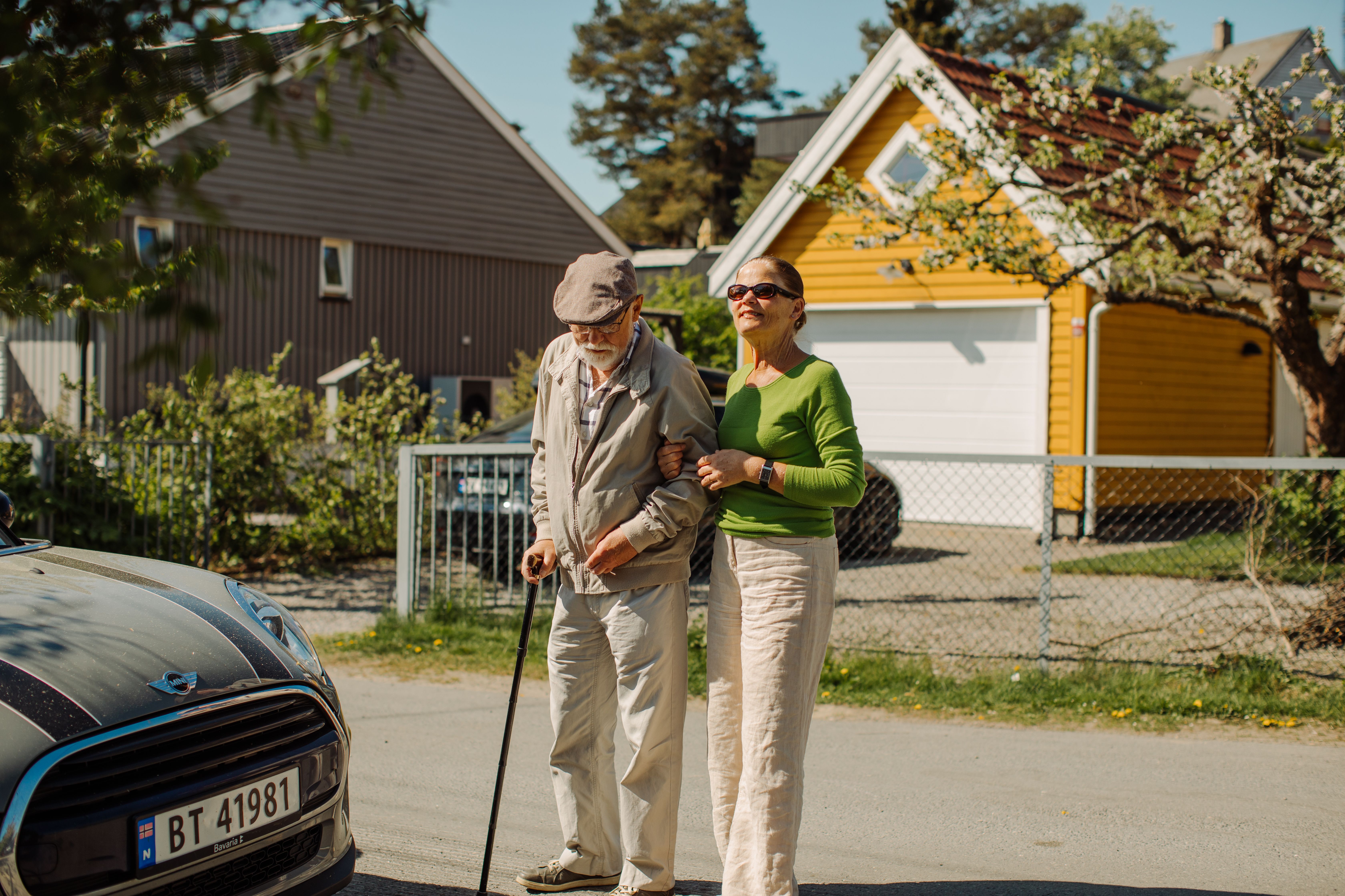 En dame leier en eldre herre med stokk