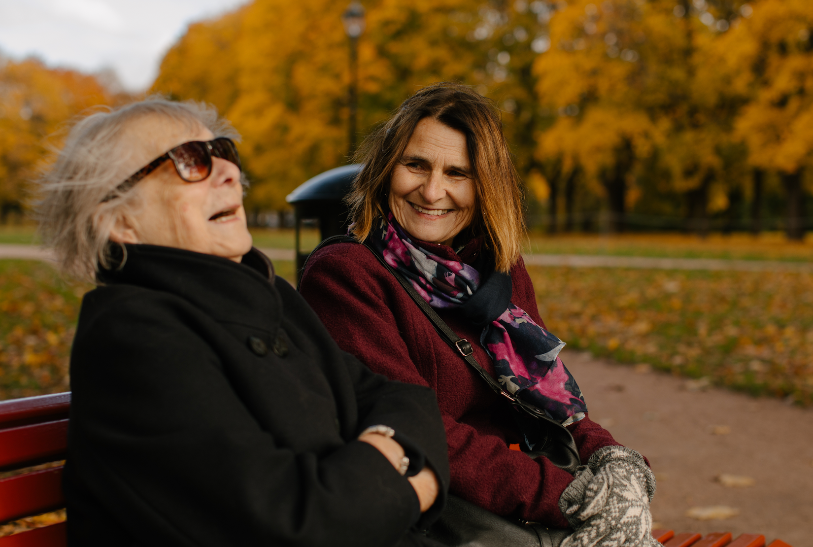 To damer sitter ute på en benk og ler