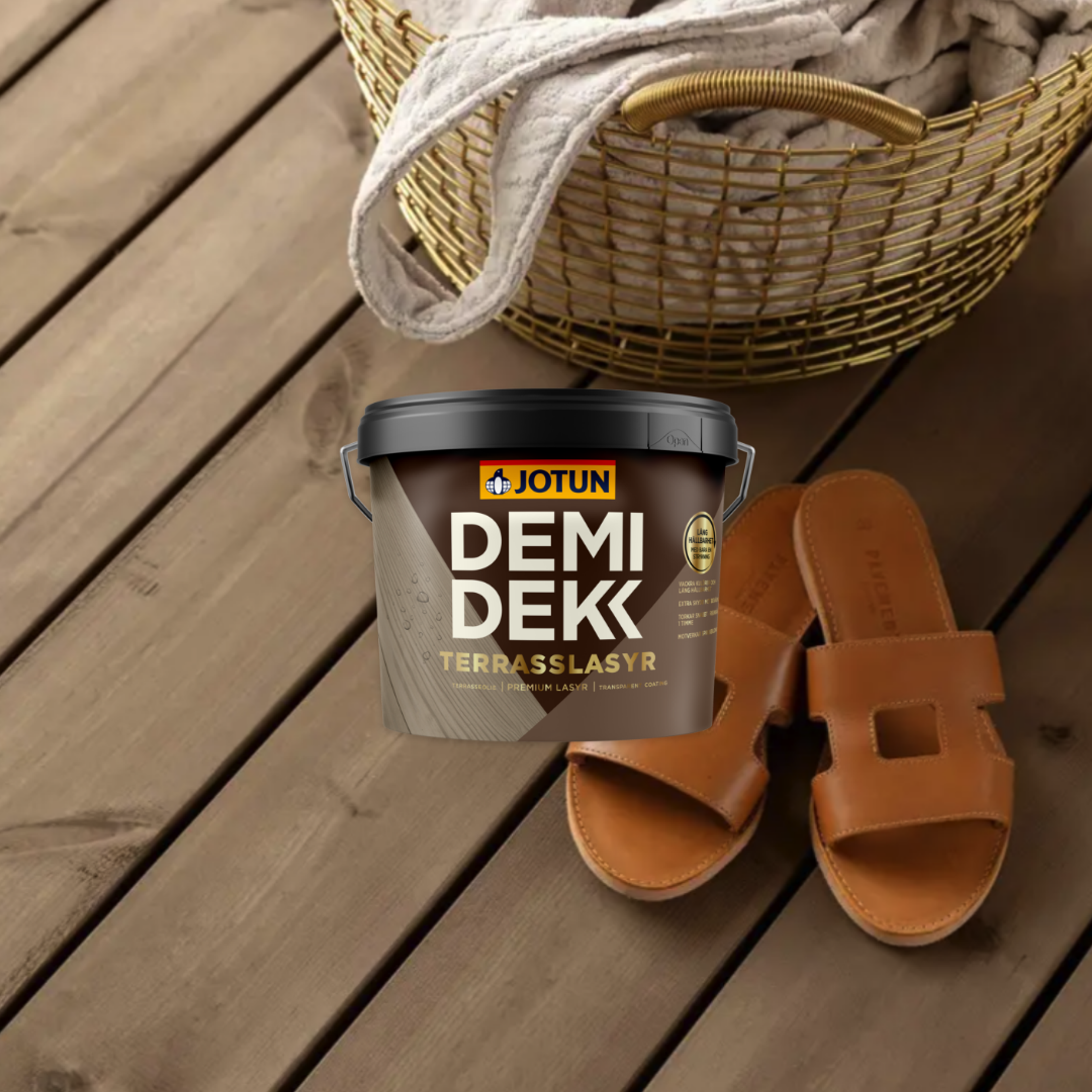 A bucket of Jotun Demidekk Terrasslasyr deck stain and brown sandals on a wooden deck with a golden basket in the background.