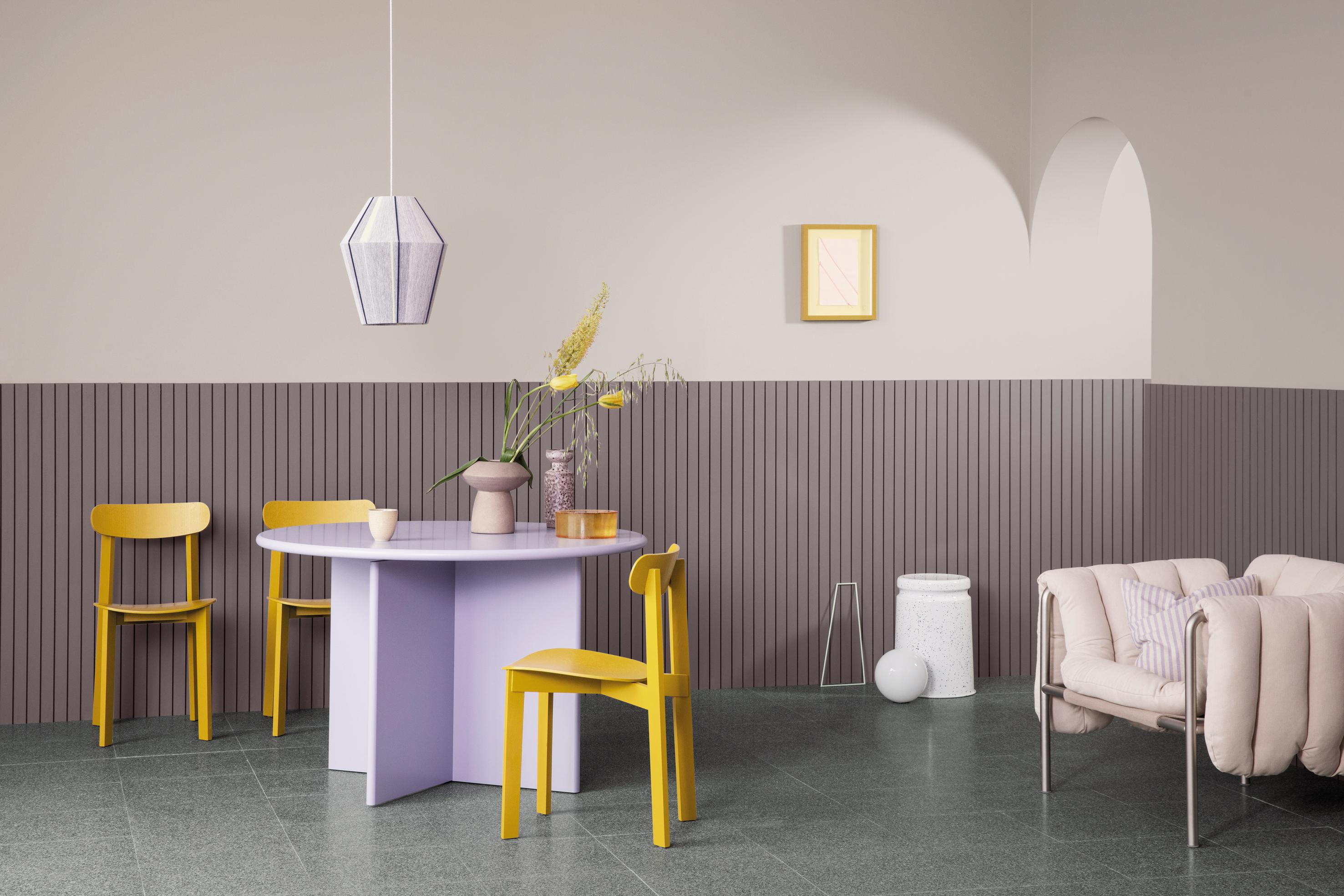 An open terracotta-colored door and frame lead into a living room with pale pink wainscoting, a beige sofa, and herringbone wood floor.