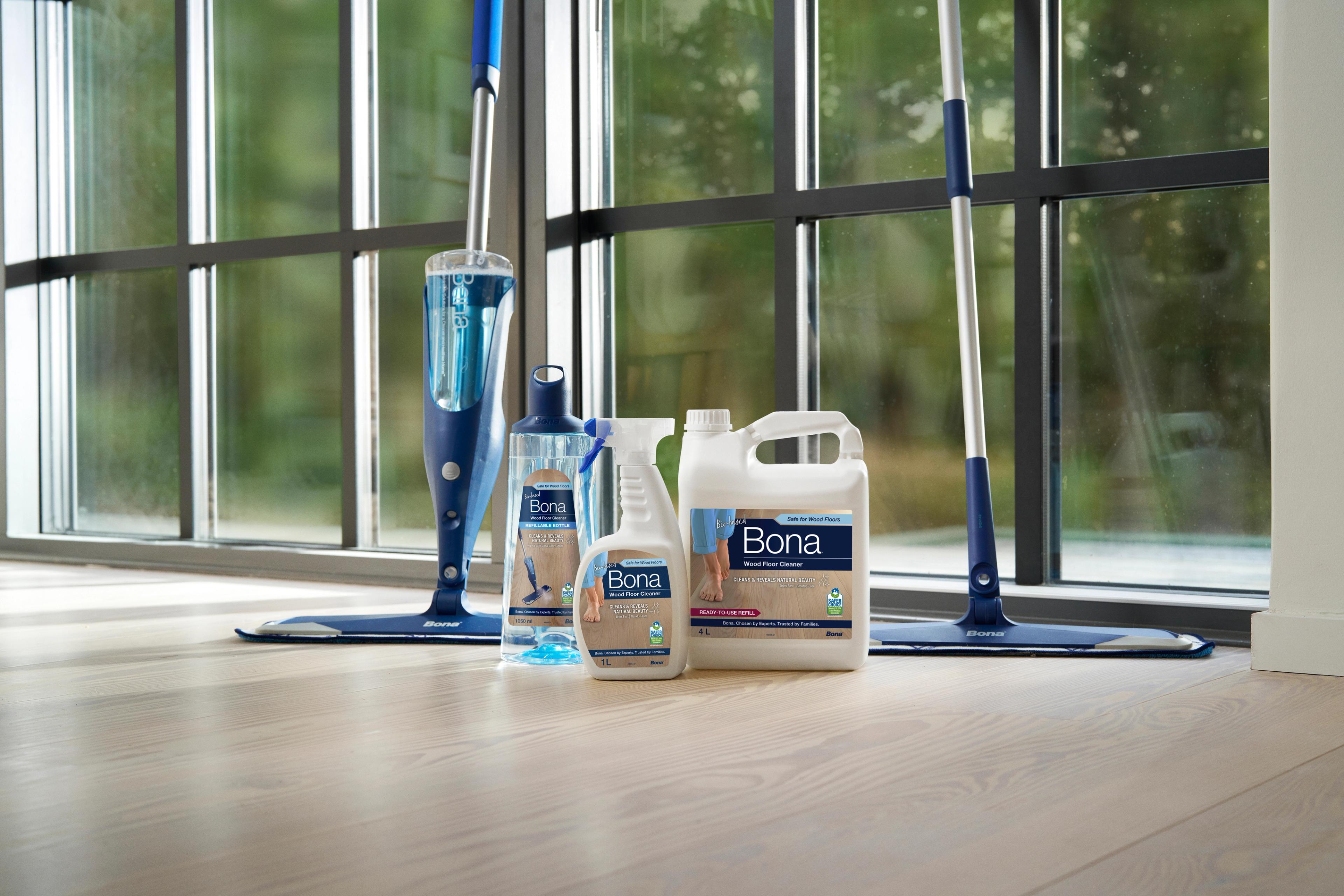 Bona mops and floor cleaning products on a light wood floor in front of a large window.