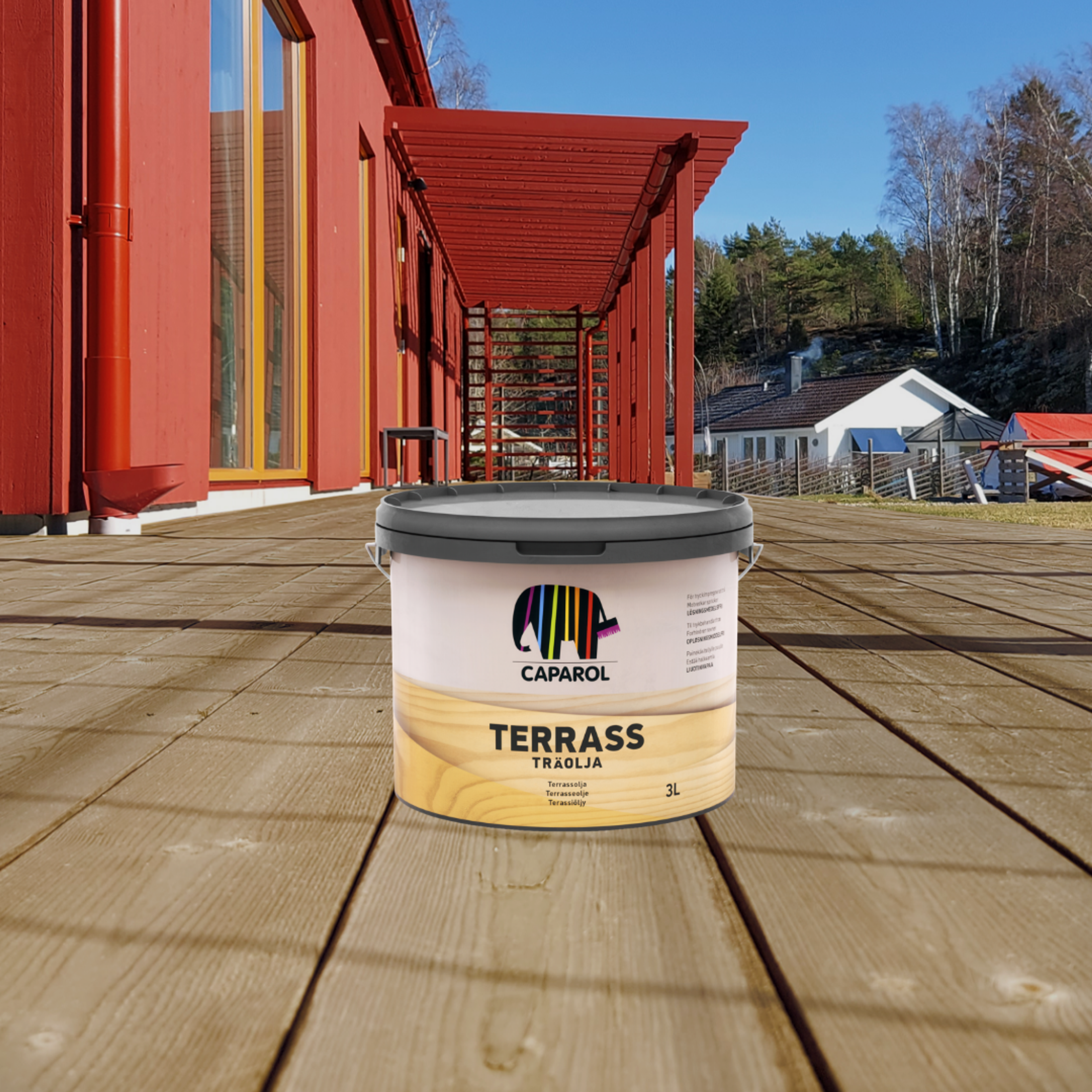 A bucket of Caparol Terrass Traolja sits on a wooden deck in front of a red house and pergola.