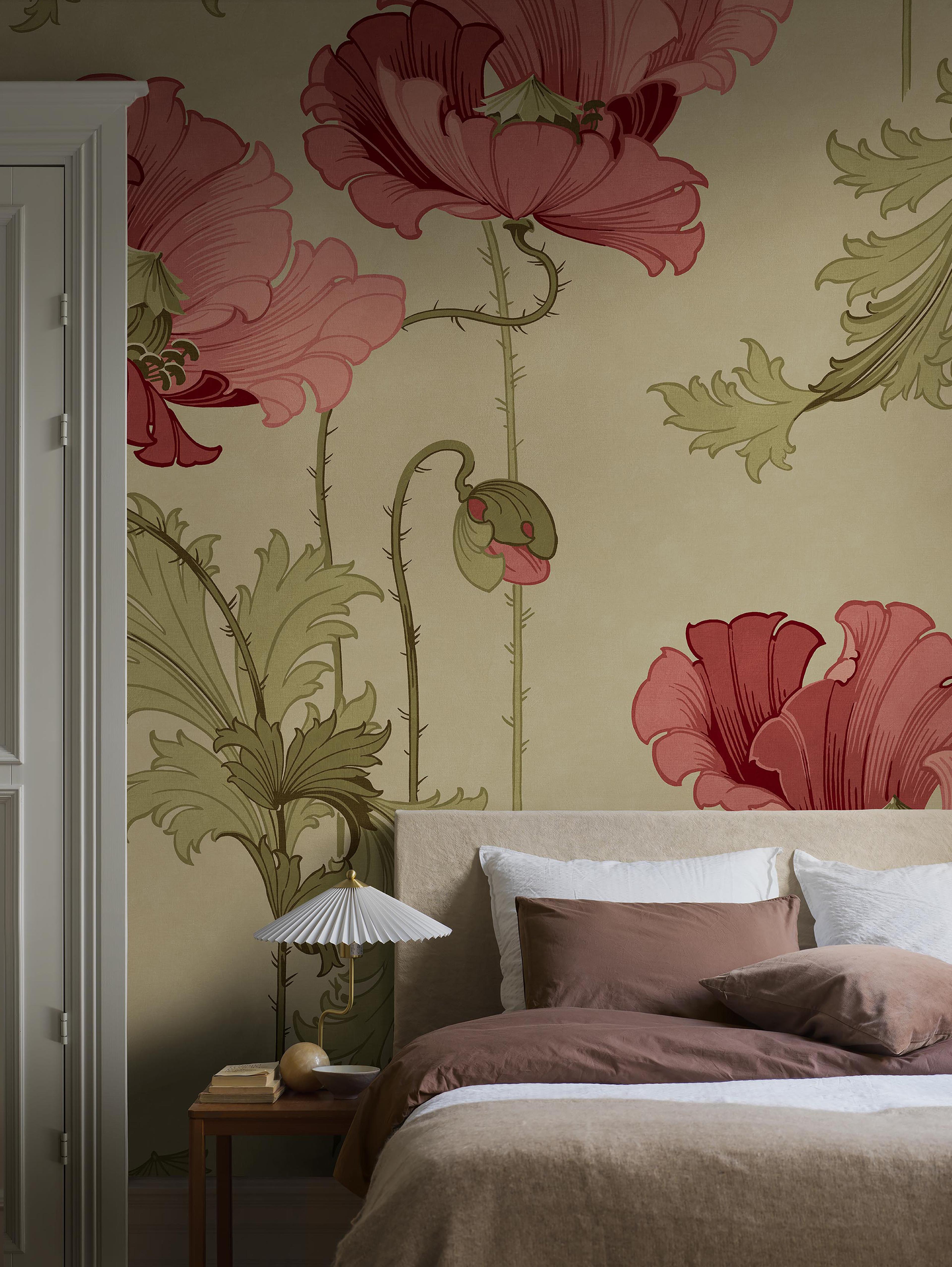 A bedroom with wallpaper featuring large pink and red poppy flowers and a bed with brown and white bedding.