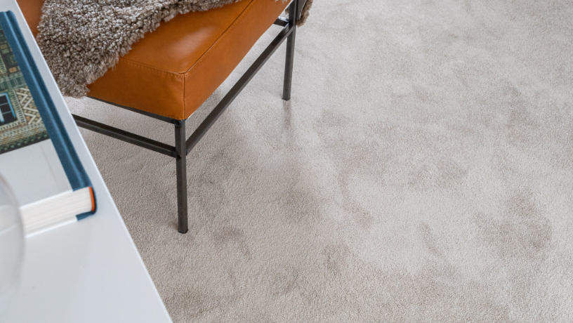 Light-colored carpet with a brown leather chair and a book on a white table.