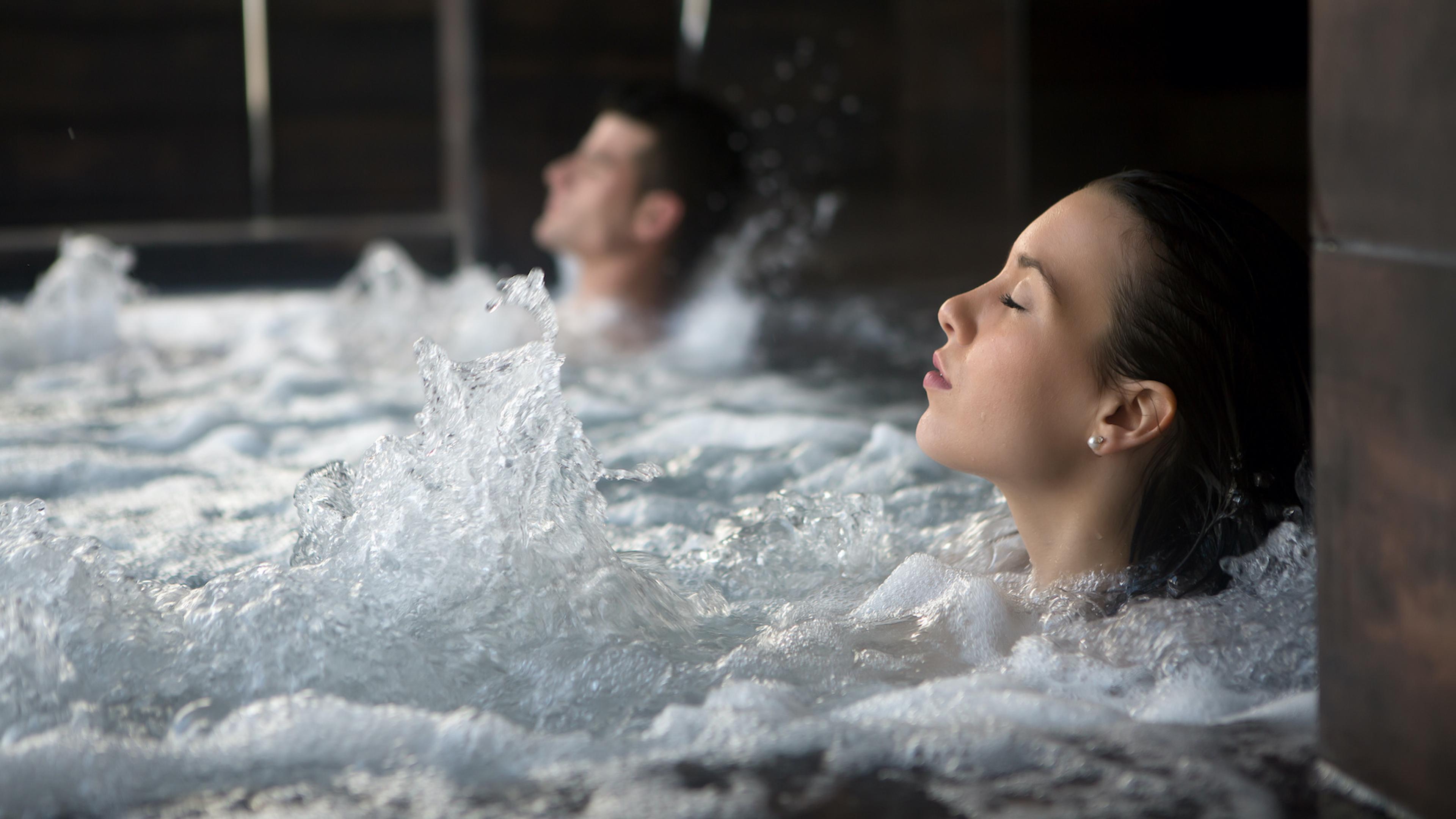 Woman and man relaxing in a bubbling hot tub.