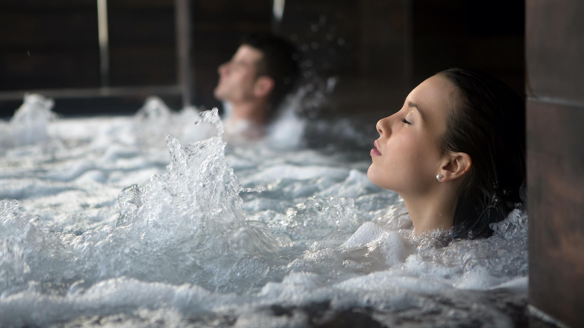 Woman and man relaxing in a bubbling hot tub.
