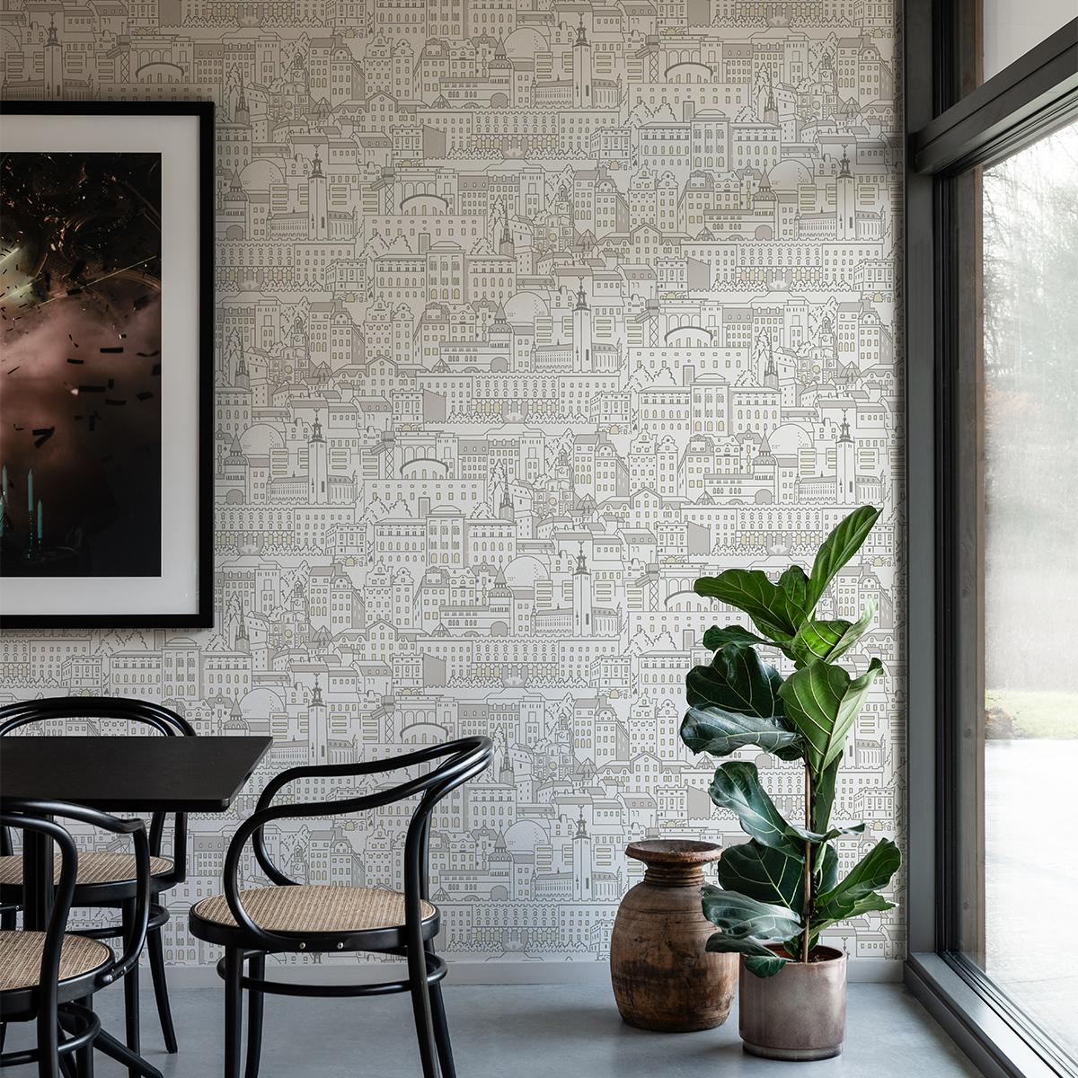 A room with city skyline wallpaper, a black table and chairs, a large fiddle leaf fig plant, and an abstract framed art piece.