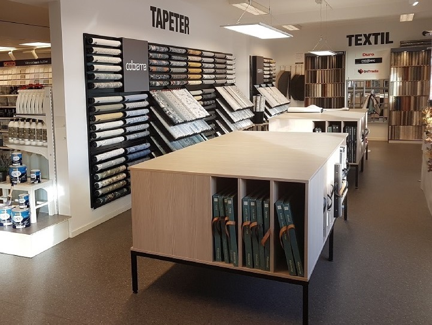 Interior view of a home decor store with wallpaper and textile samples on display.