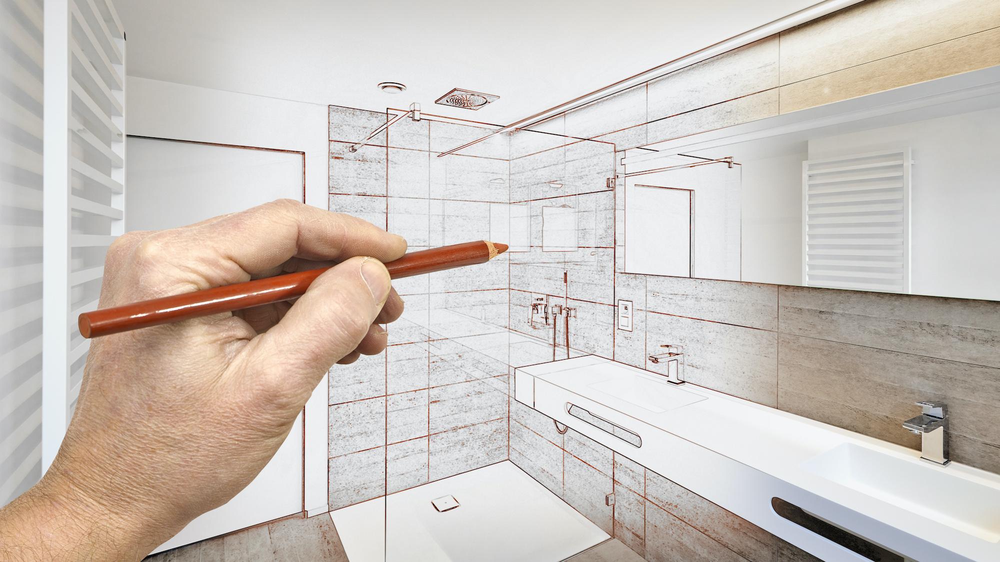 A hand holding a pencil draws a modern bathroom, transitioning from sketch to finished design.