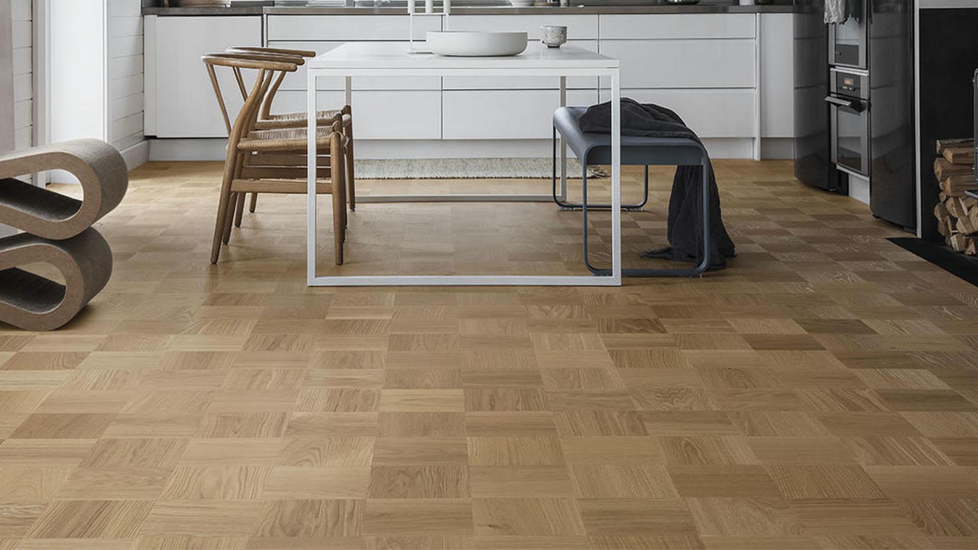 A modern kitchen and dining area with light wood parquet flooring.