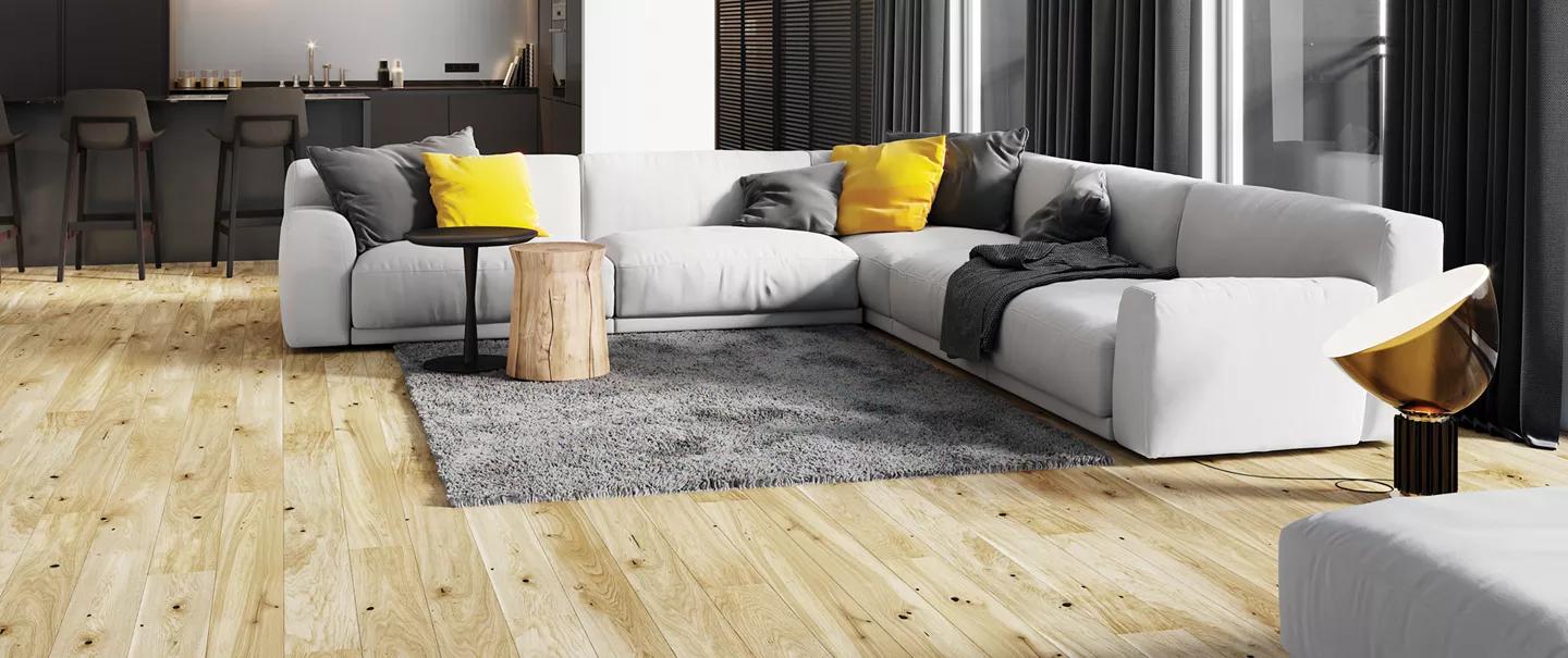 Modern living room with a white sectional sofa, yellow and grey pillows, a grey rug, and light wood flooring.