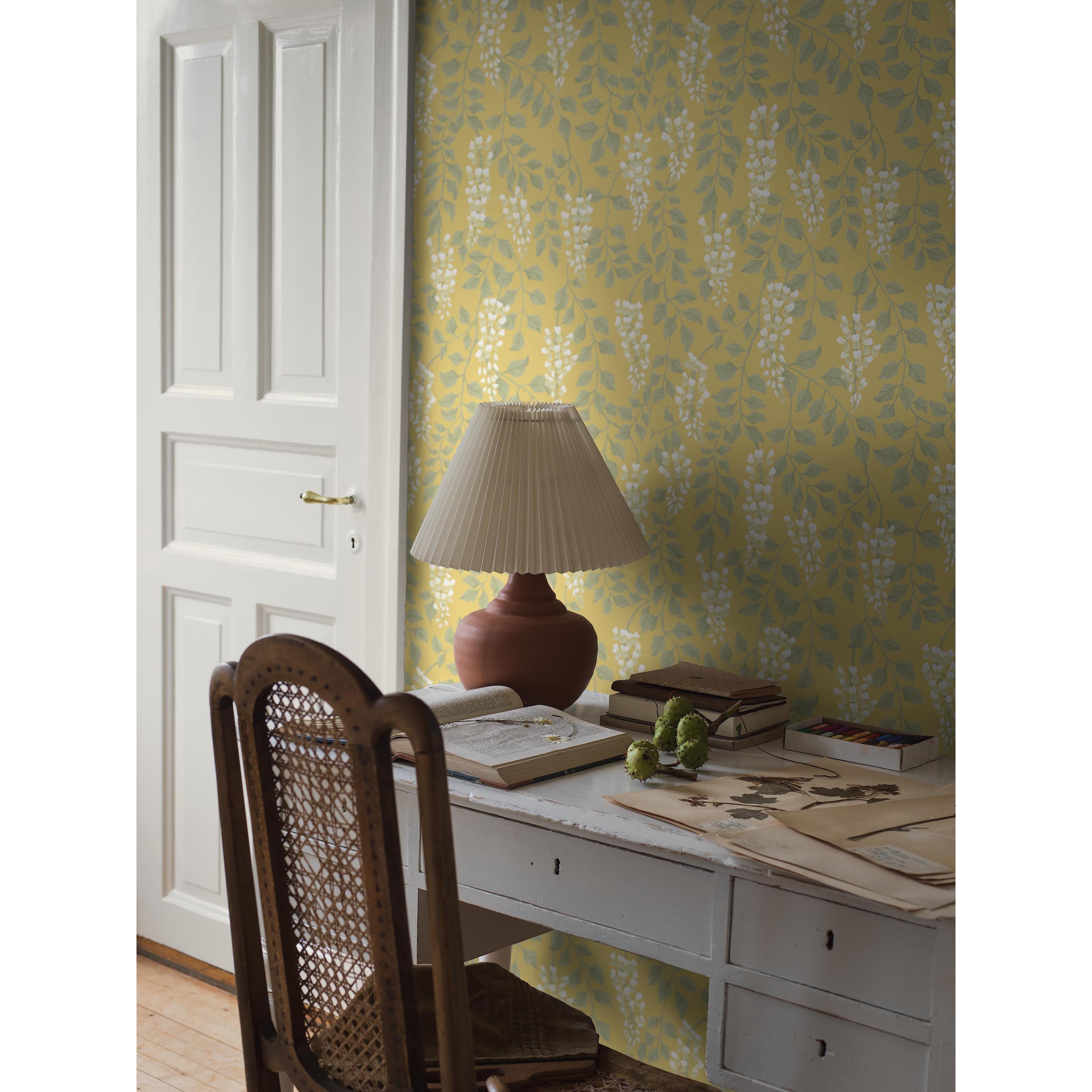 Blåregn gul, tapet tapet med botaniskt, blommigt mönster i gul. Från kollektionen Orangeri. Nonwoven-material med förskjuten passning. Passar i vardagsrum och kök.