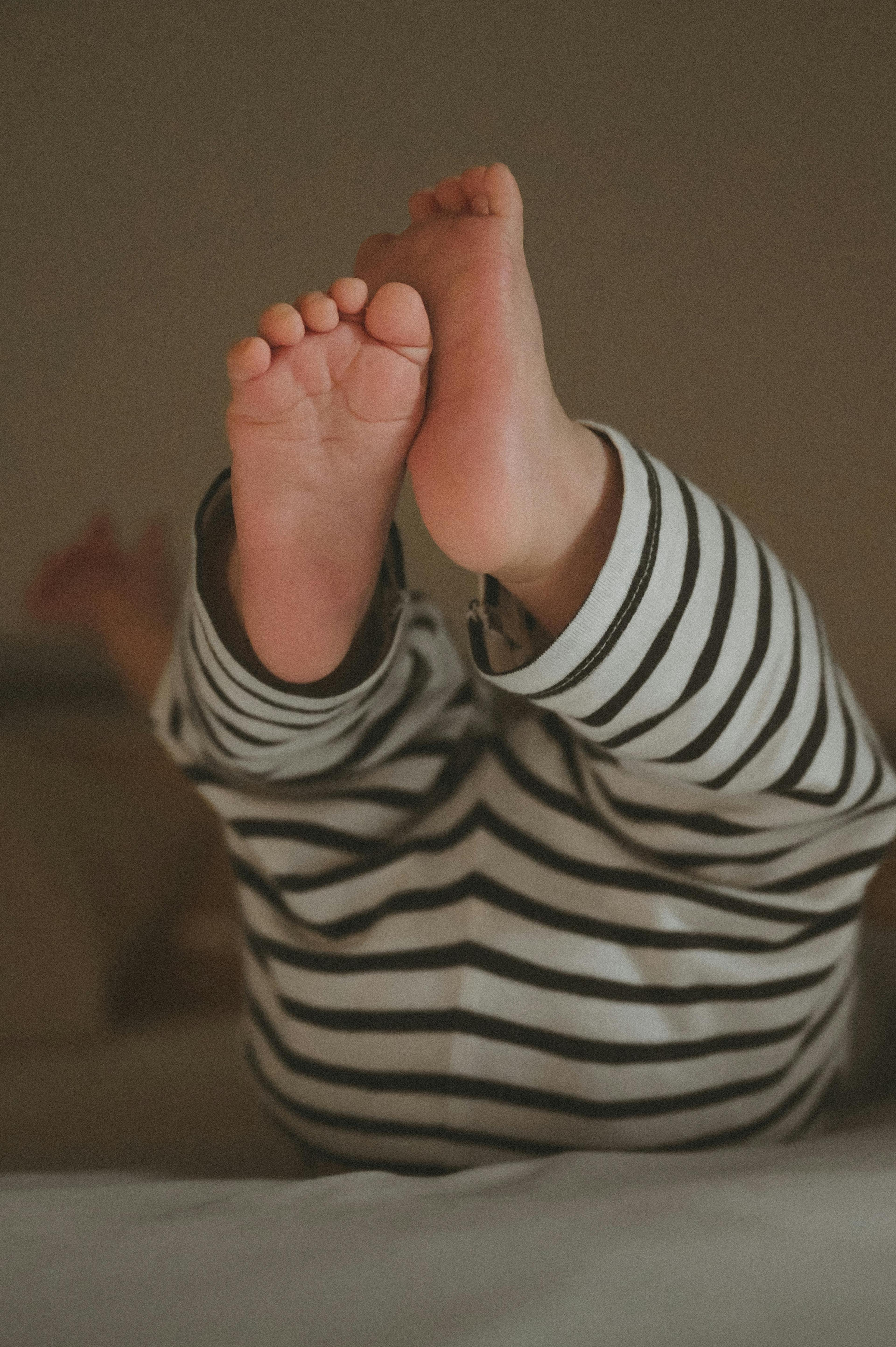 Close-up of a baby's raised feet wearing striped pajamas.