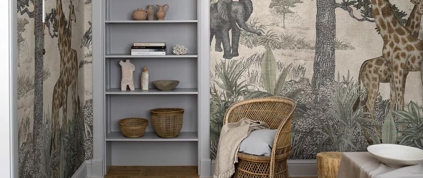 A room with safari animal wallpaper, a grey bookshelf, and a wicker chair.