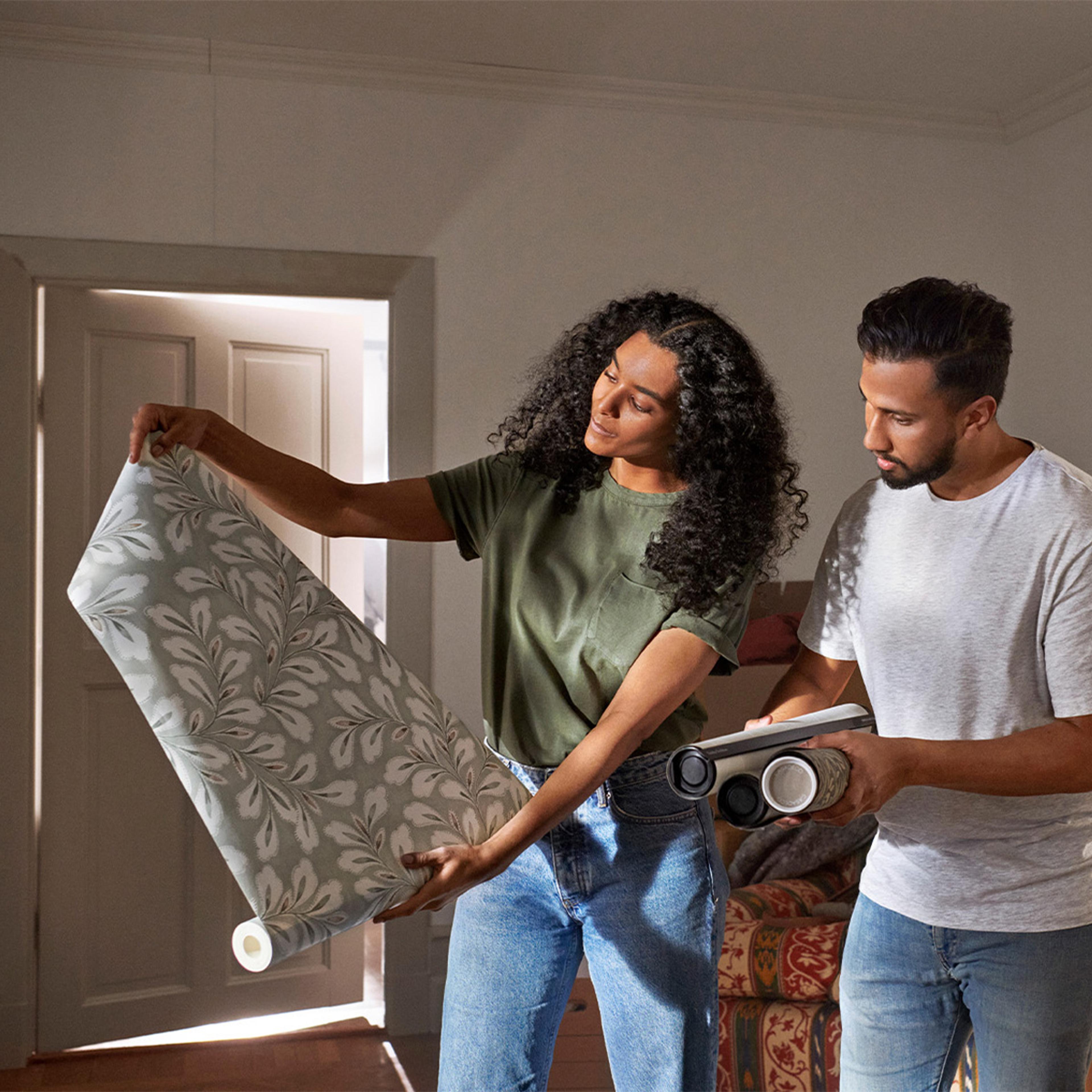 A couple examines rolls of patterned wallpaper.