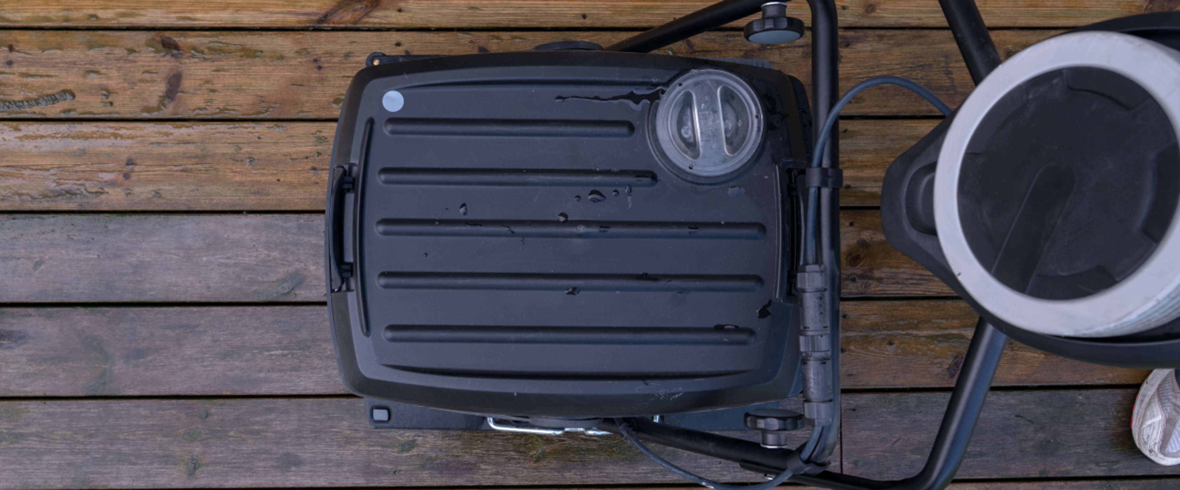 Top-down view of a black portable grill on a wooden deck.