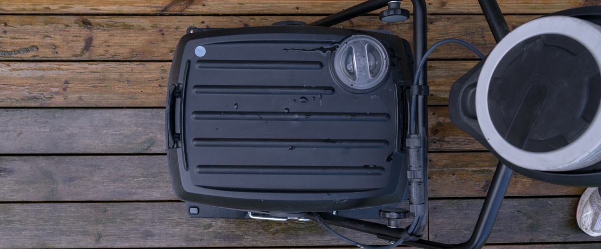 Top-down view of a black portable grill on a wooden deck.