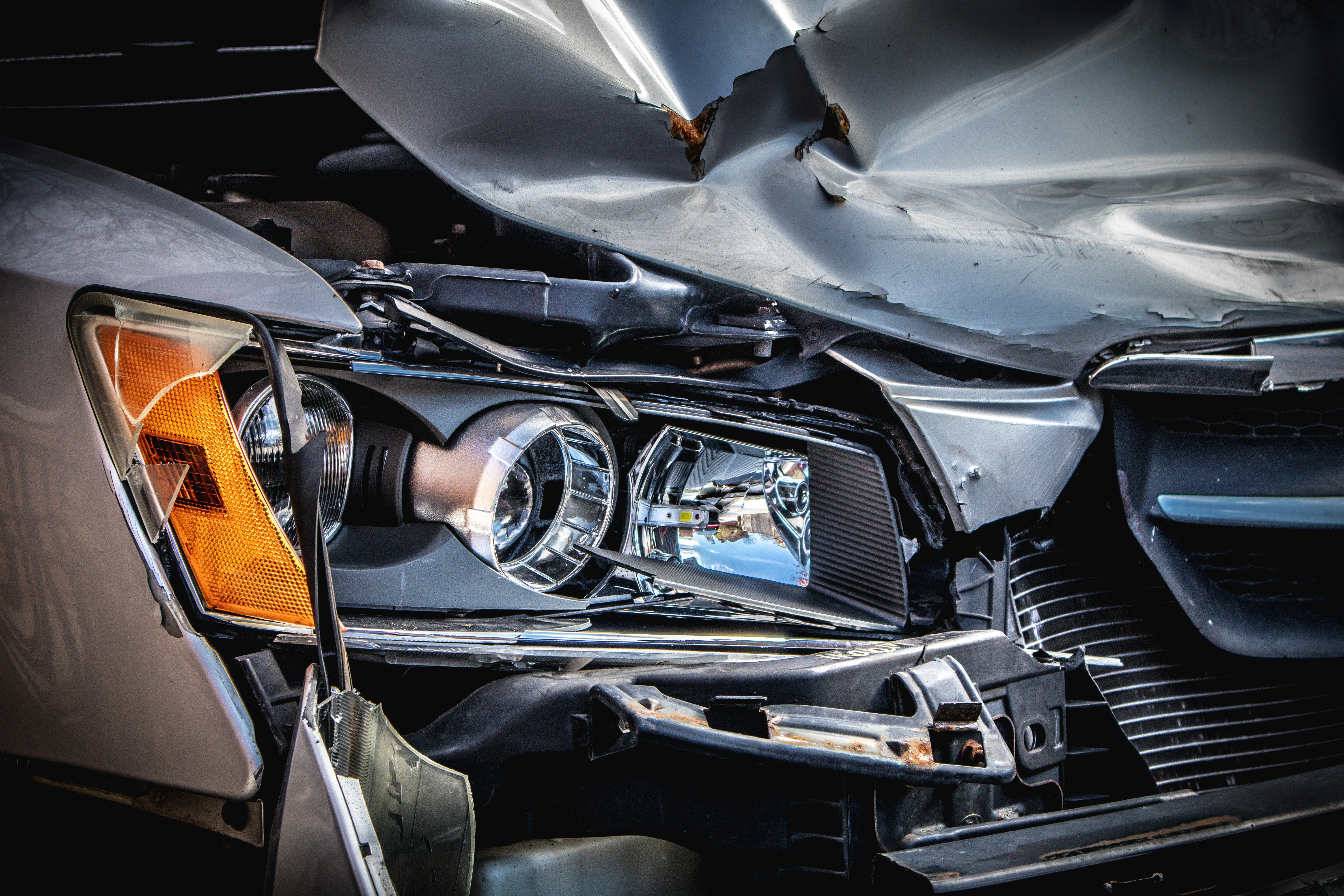 Close-up of front-end crash damage on a silver car with a broken headlight and crumpled hood after a Pennsylvania car accident.