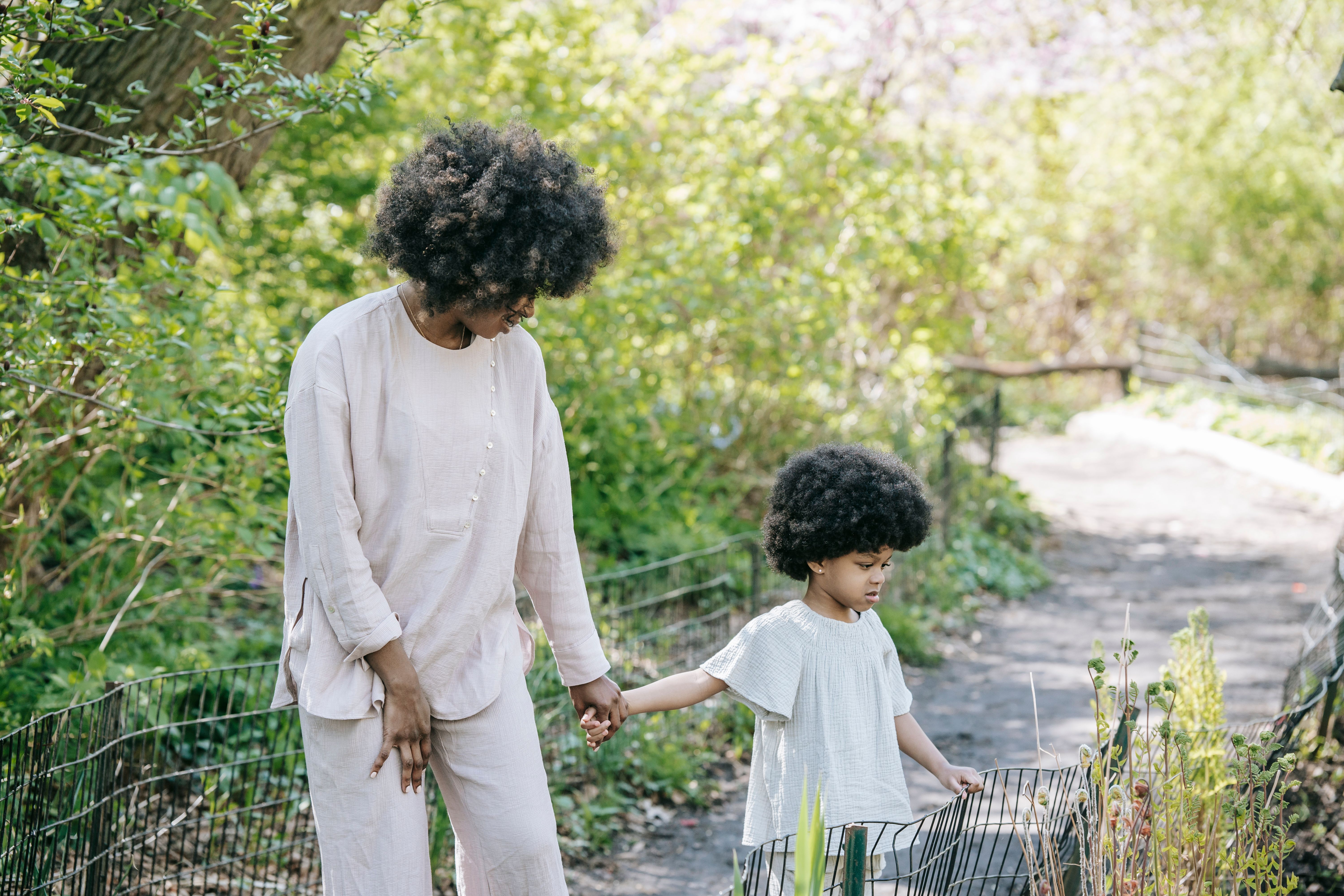 A mother and young daughter walk hand in hand through a quiet green park, a tender moment that captures the irreplaceable bond wrongful death leaves behind.