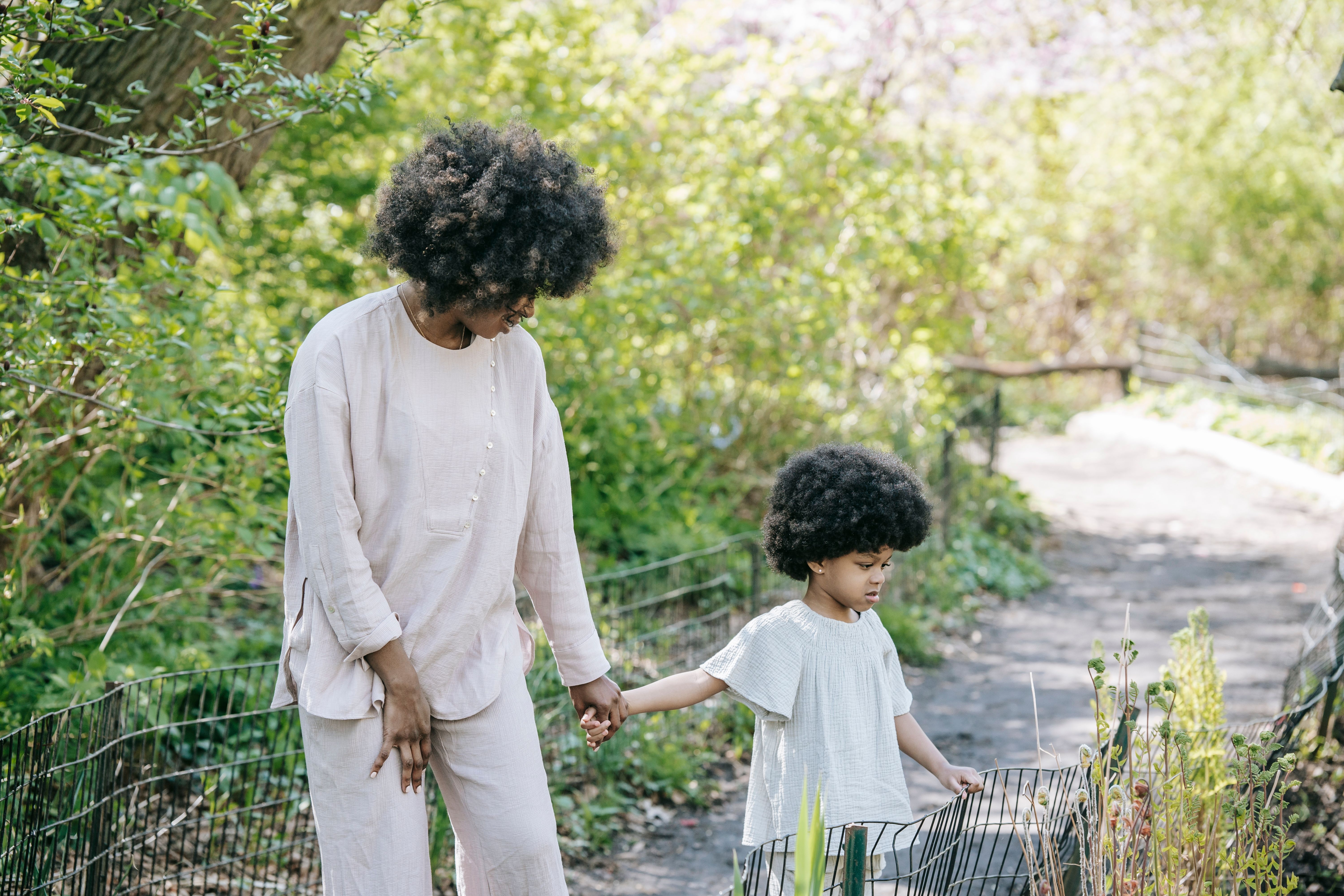 Image A mother and young daughter walk hand in hand through a quiet green park, a tender moment that captures the irreplaceable bond wrongful death leaves behind.