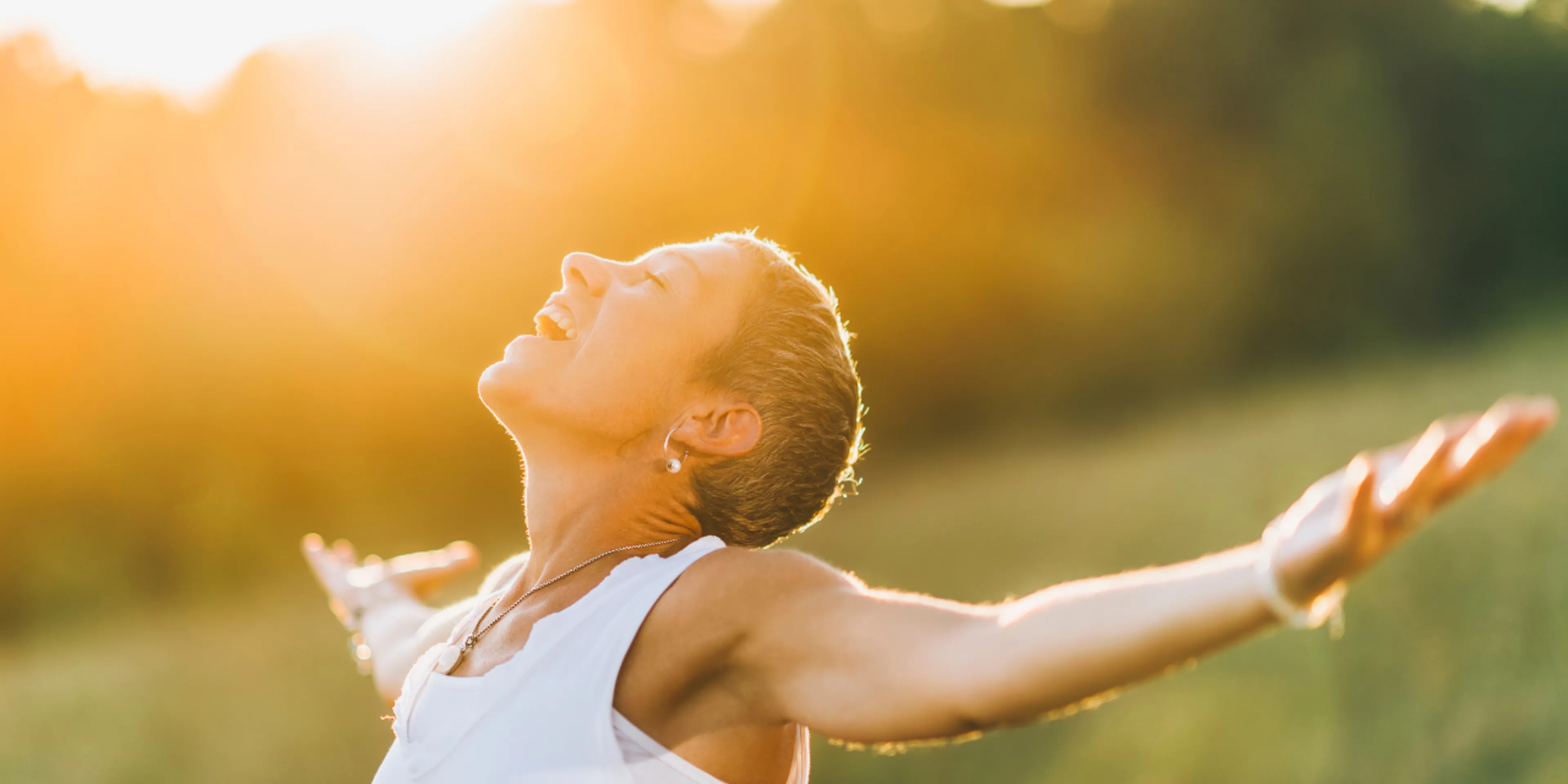 woman looking up at the sky with open arms and a smile