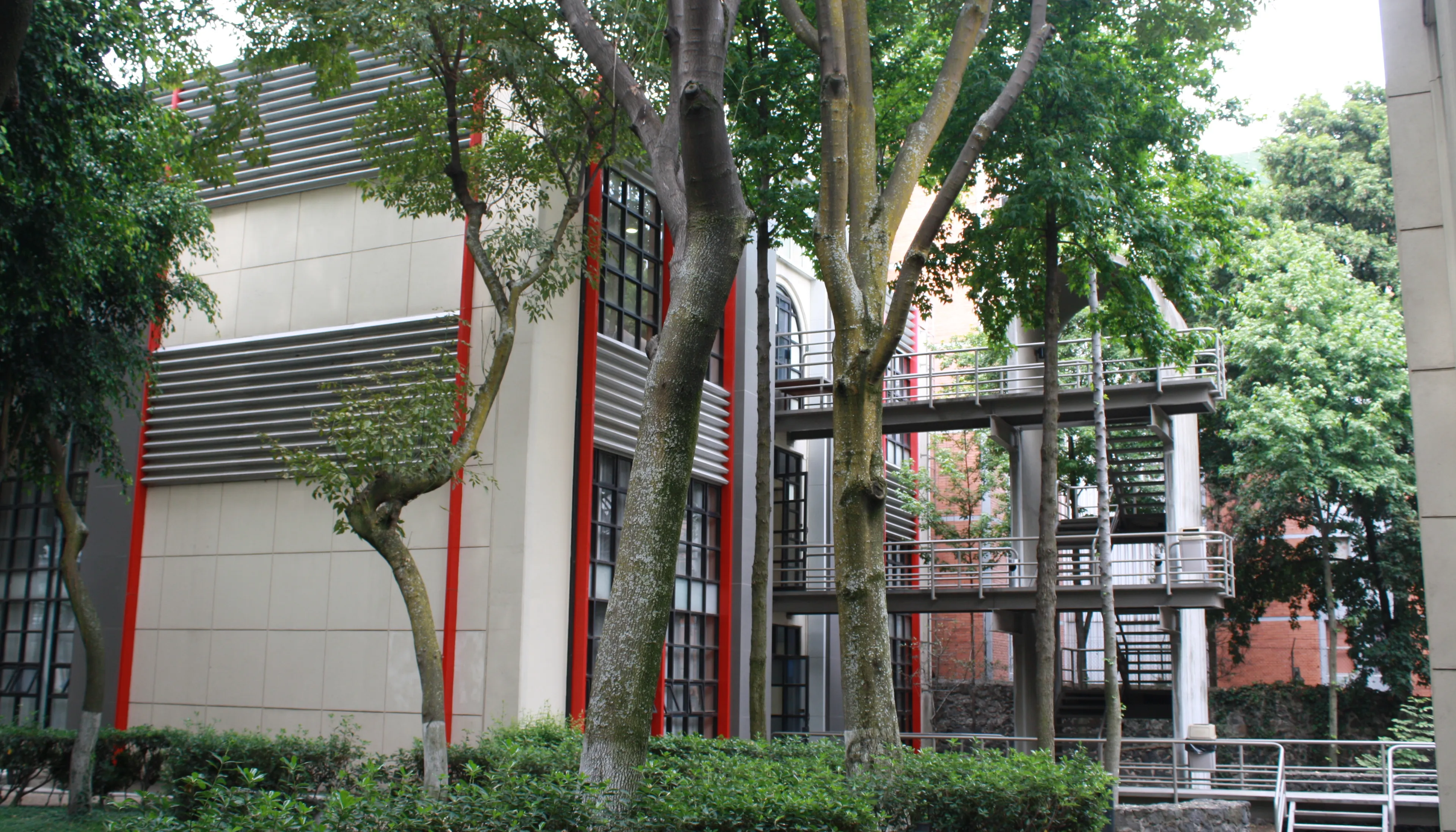 Edificio universitario ITAM con pasarelas y escaleras exteriores entre árboles, mostrando infraestructura académica y espacios de formación profesional.