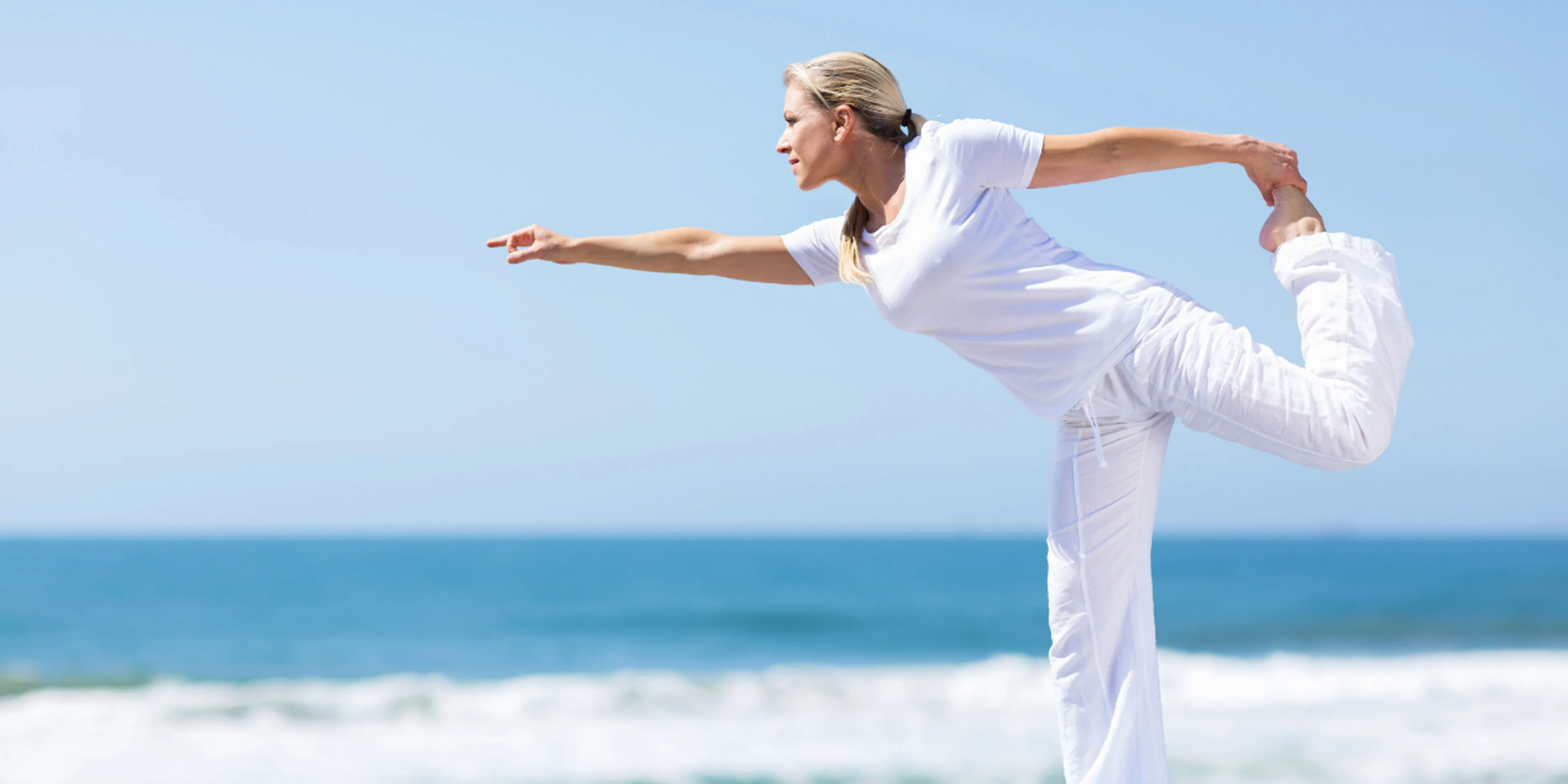 Mujer haciendo yoga a la orilla del mar