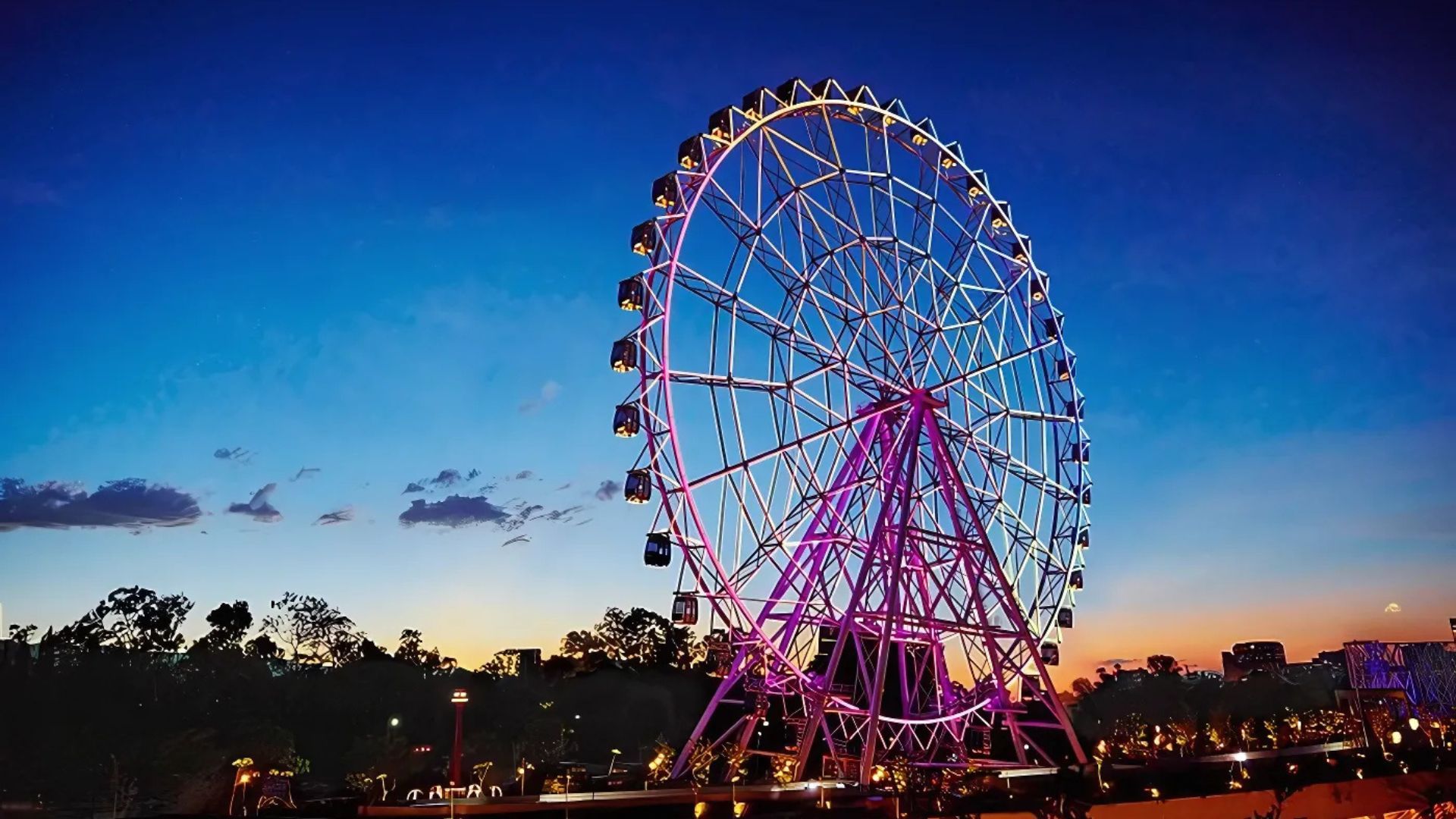 Rueda de la fortuna iluminada al atardecer en Aztlán Parque Urbano.