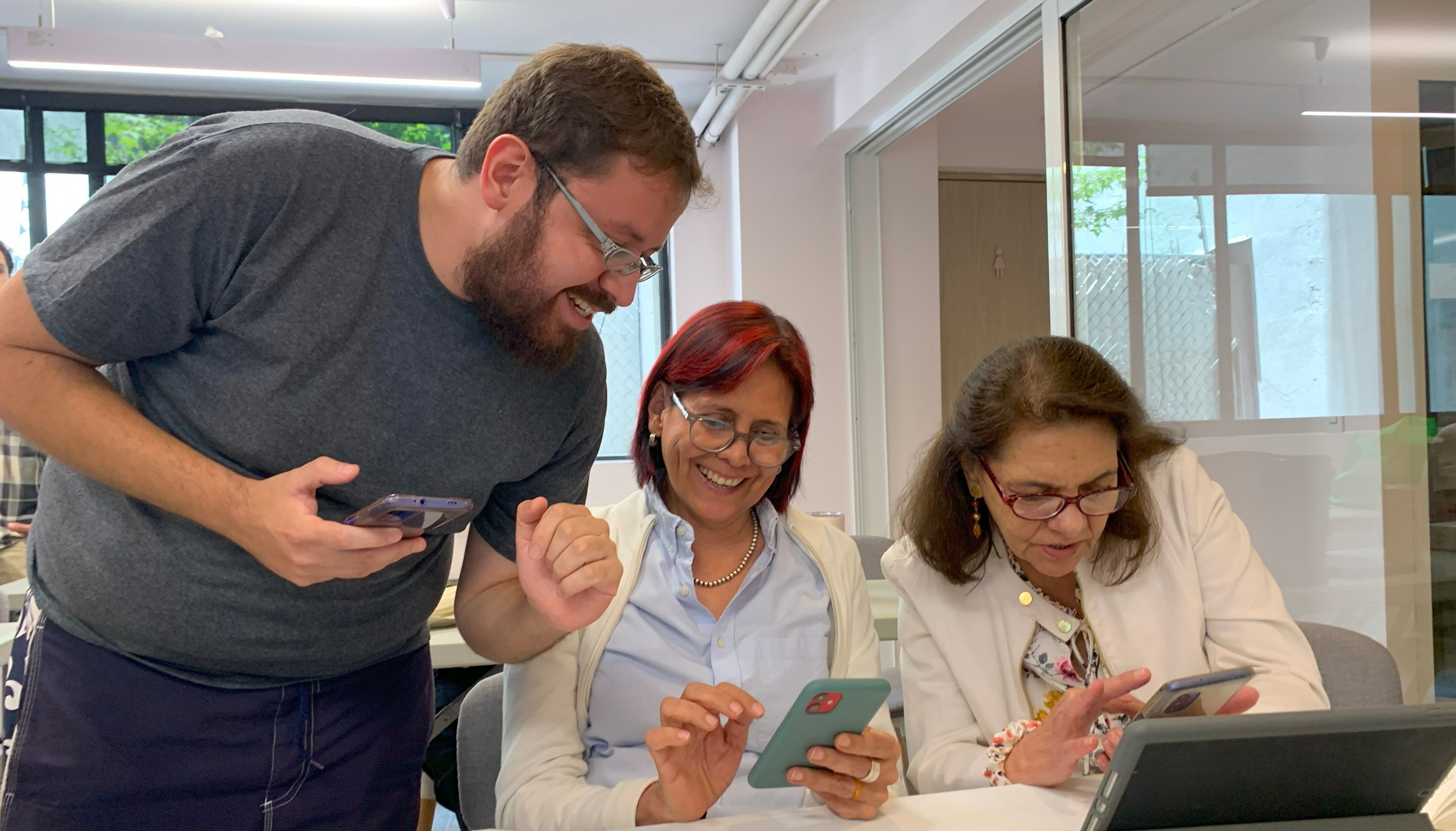 profesor enseñando a dos alumnas a usar celular