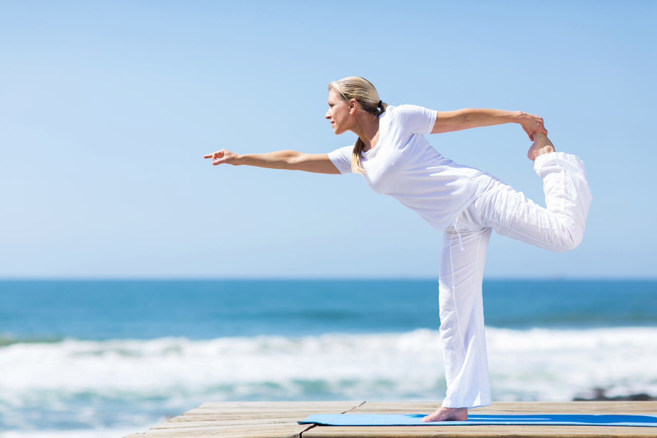 Mujer haciendo yoga a la orilla del mar