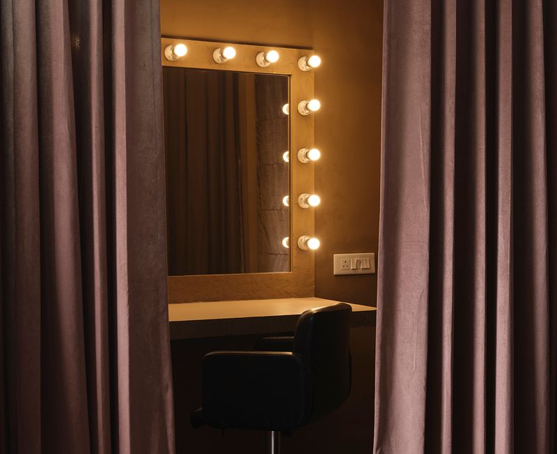Private makeup and vanity station inside a studio rental, featuring warm lighting, a backlit mirror, and velvet curtains — ideal for photo shoots, fashion styling, and video productions booked via BOOKD in India.