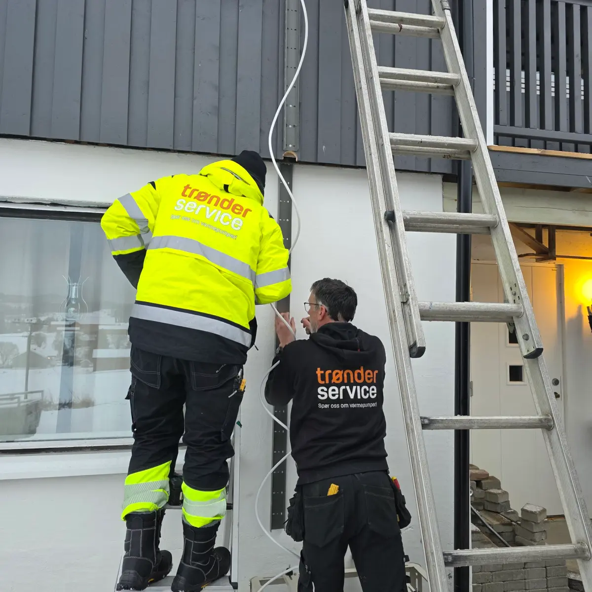 To montører fra Trønderservice ler sammen på vei inn til et oppdrag