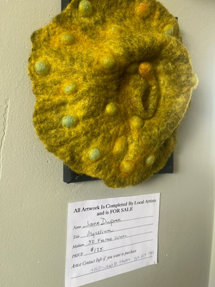 Photo of a small 3-D felted organic shaped sculpture. The colors are yellow, green and gold.