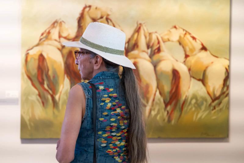 Annie Barker in front of horses painted by Susie Alexander