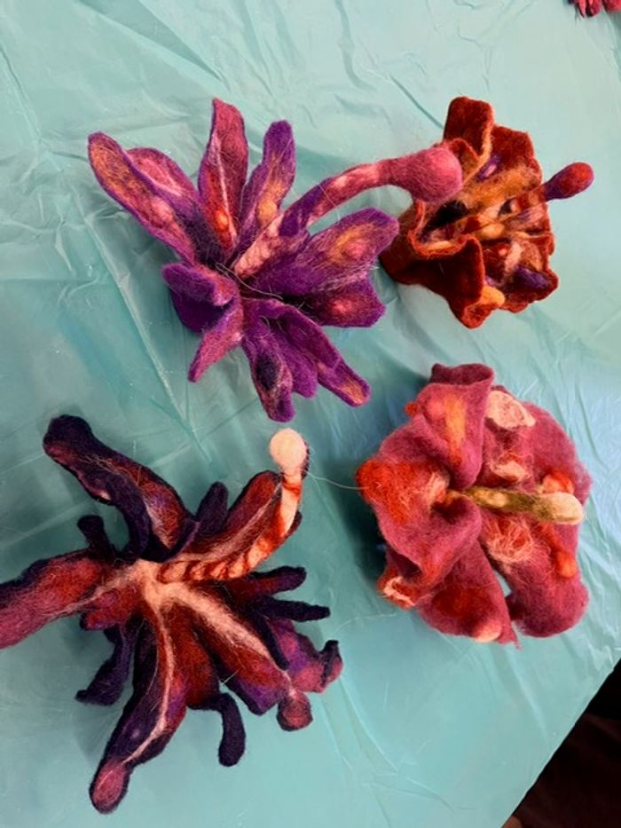 Photo of 4 small felted 3-D organic shaped sculptures. The colors are red, orange and purple.