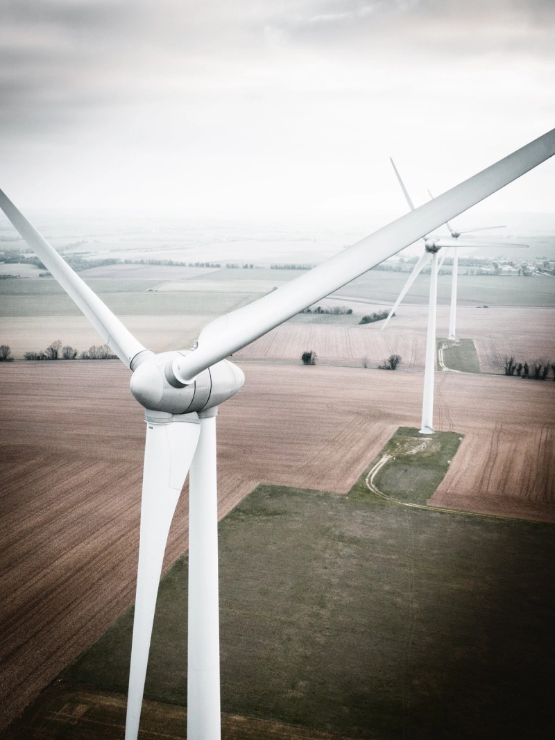 Desaturated aerial photo of white wind turbines over farm fields