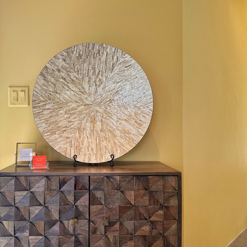 Hall table against a yellow wall with large decorative plate and interior designer business cards displayed