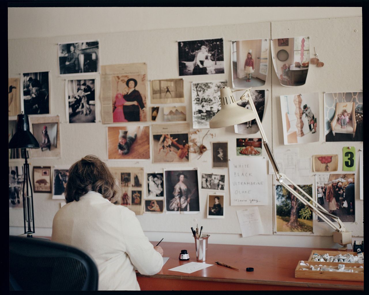 Woman working at desk with photographs on the wall