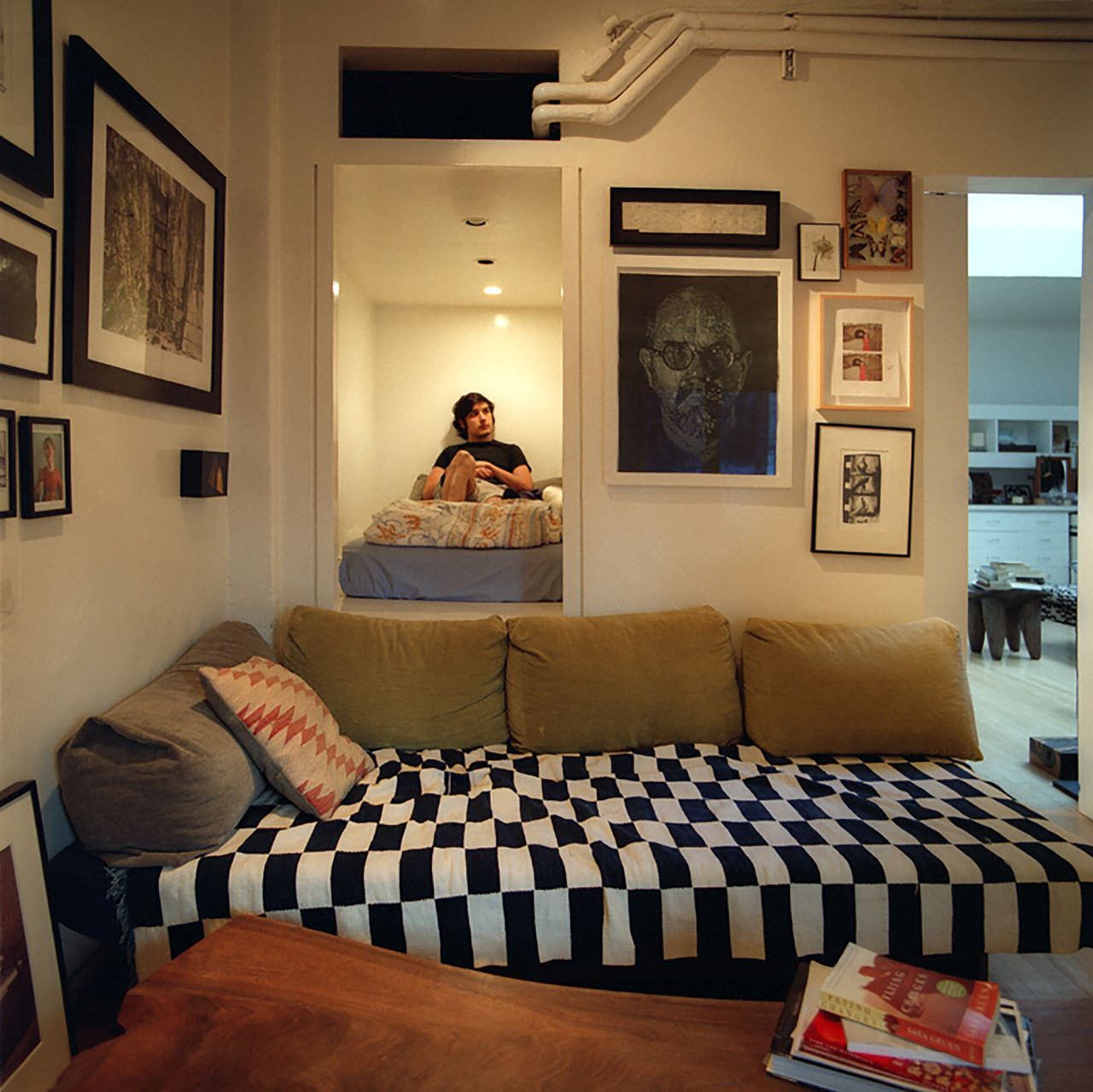 A boy sitting on a bed inside a light-filled room within an apartment