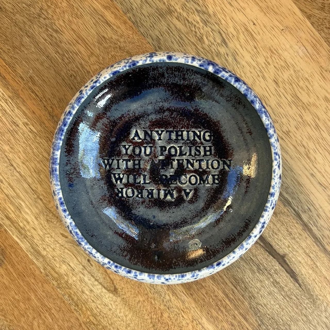 A ceramic bowl made by Popova that reads, “Anything you polish with attention will become a mirror.” (Courtesy The Marginalian)