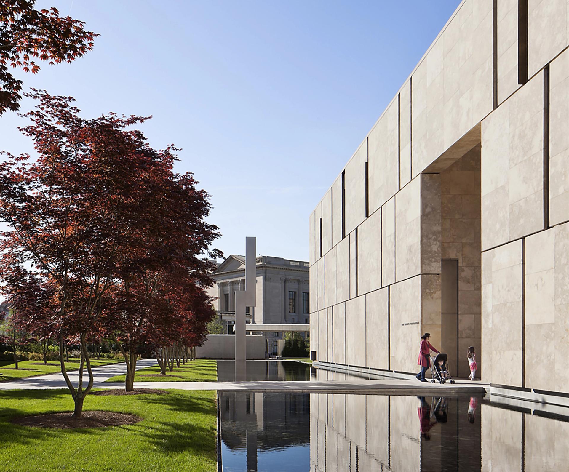 A woman and her children walk into a building surrounded by water and grass