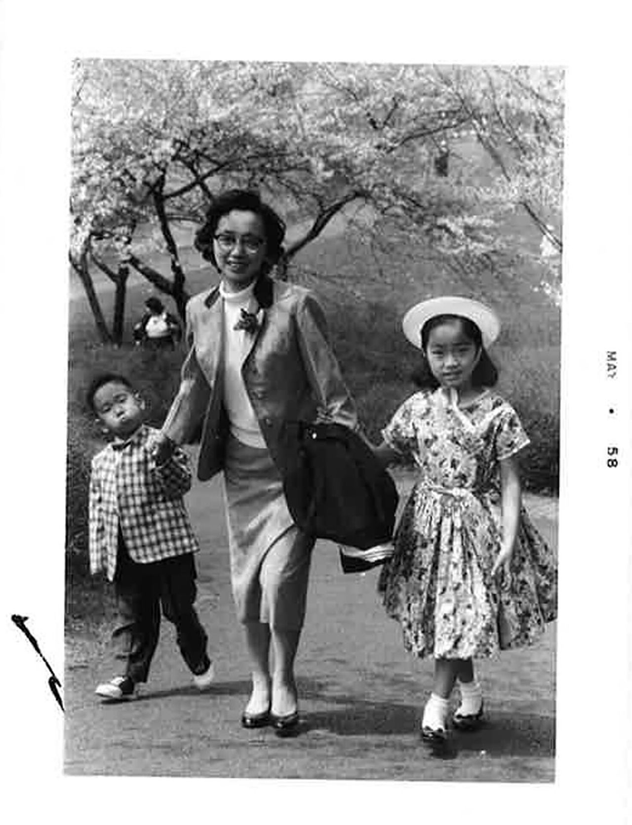 A black and white photograph of a boy and girl with their mother