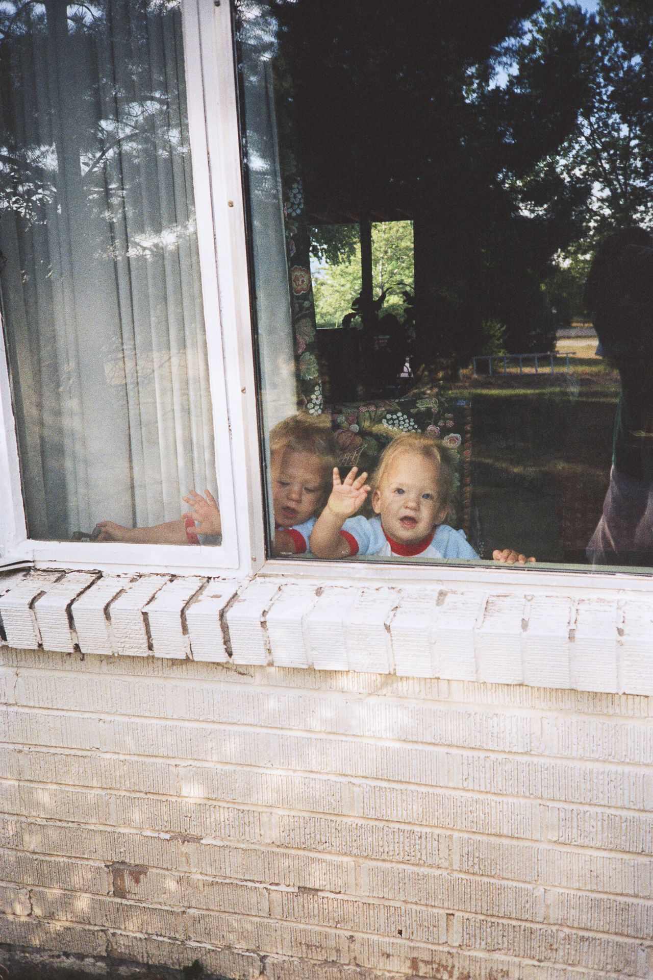 Spencer (left) and Trent (right) looking out through the living room window of their Bow Mar, Colorado, home at their mother taking the photo.