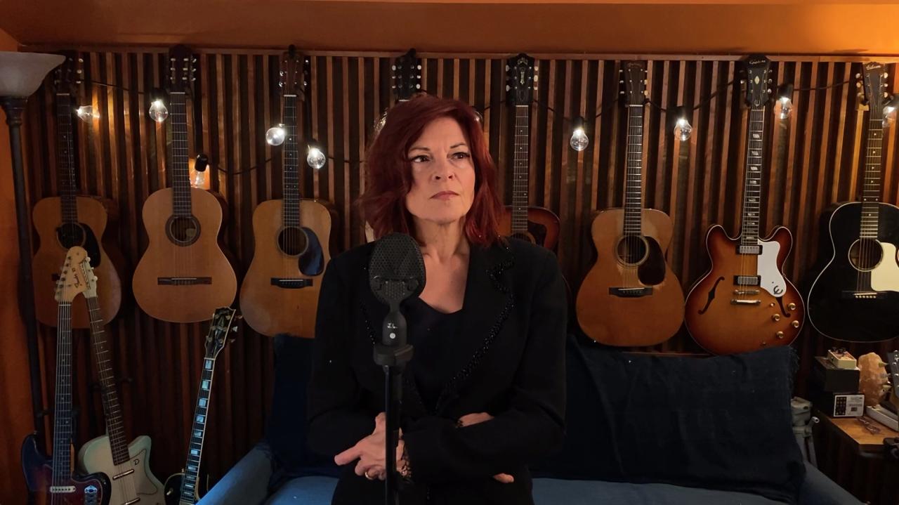 Singer Rosanne Cash stands in front of a wall covered in guitars