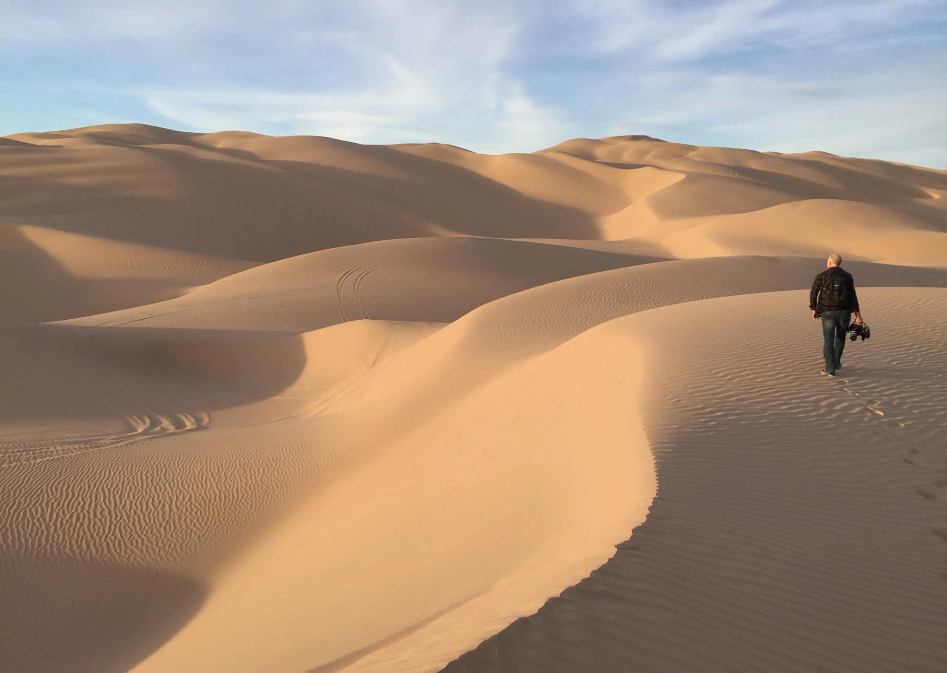 Trevor Paglen walking in the Algodones Dunes in California.